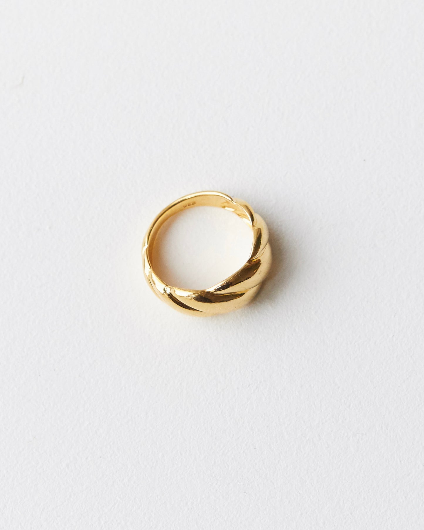 minimal twisted ring resting in soft light, sculptural and calm composition