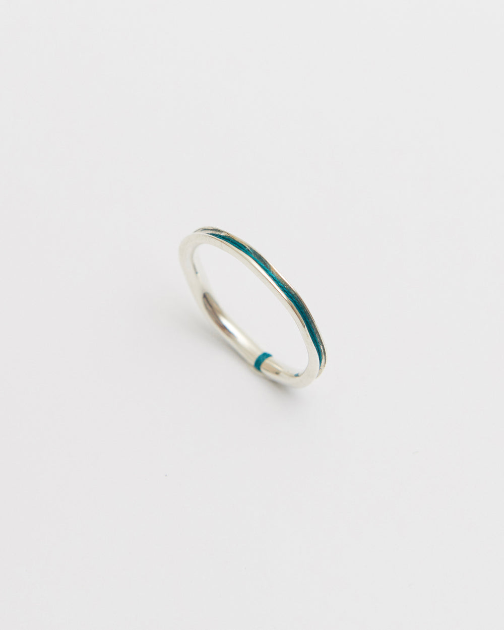 Silver ring with green nylon on a light gray background