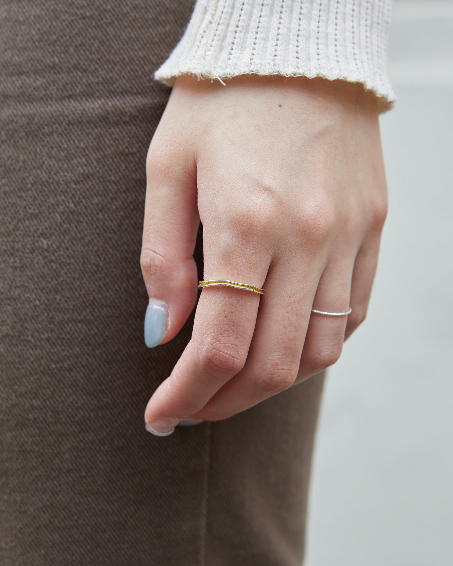 Light mustard minimalist ring worn on ring finger with other dainty silver