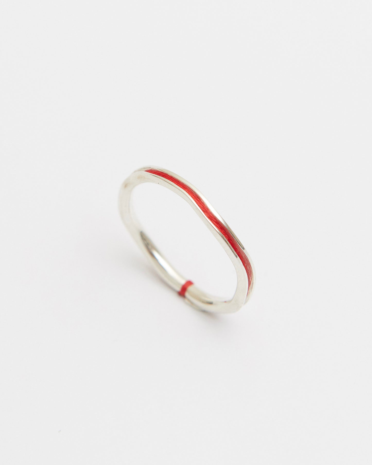 Silver ring with a thin red line on a white background