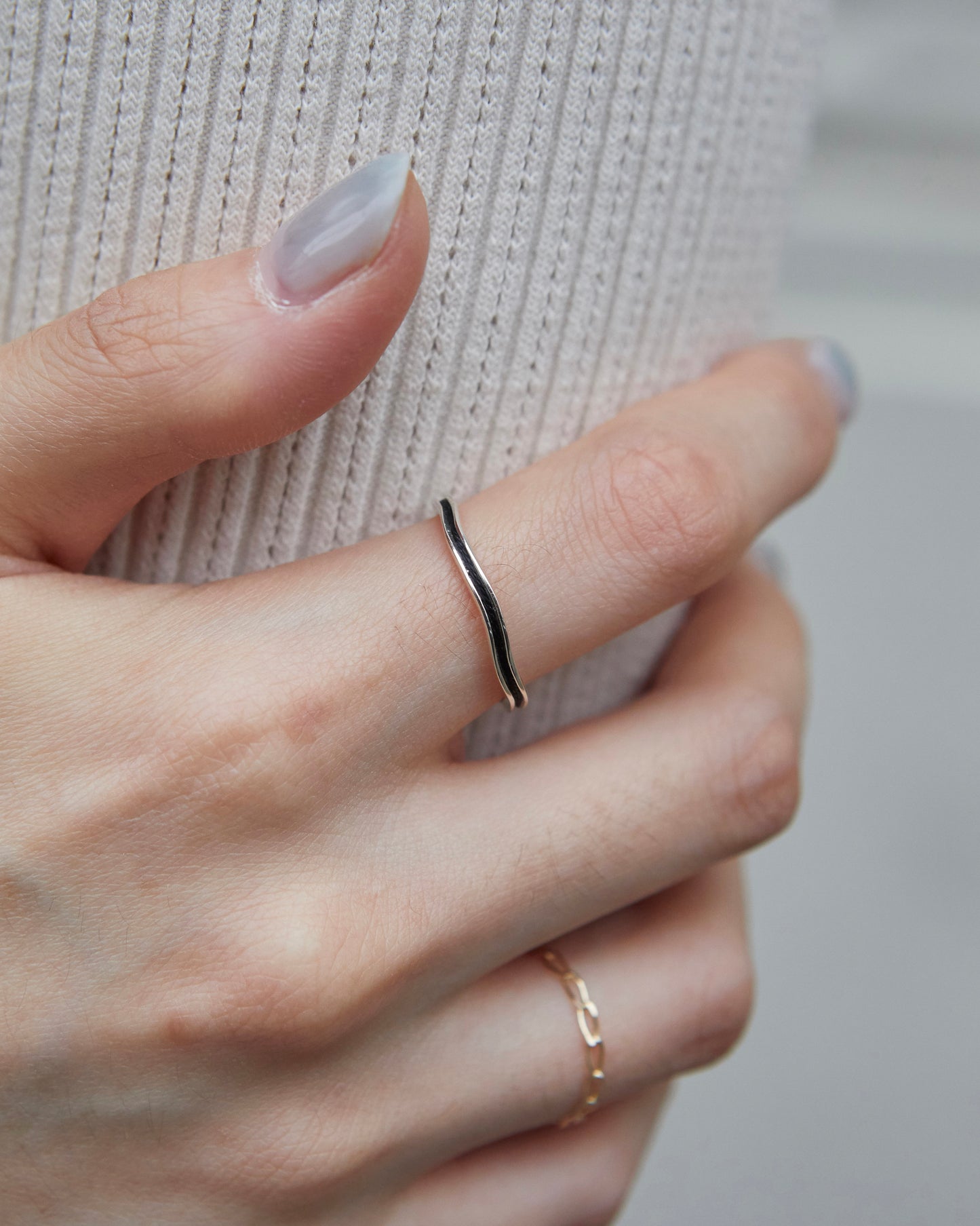 Close-up of a black-silver ring worn with gold stackers on hand