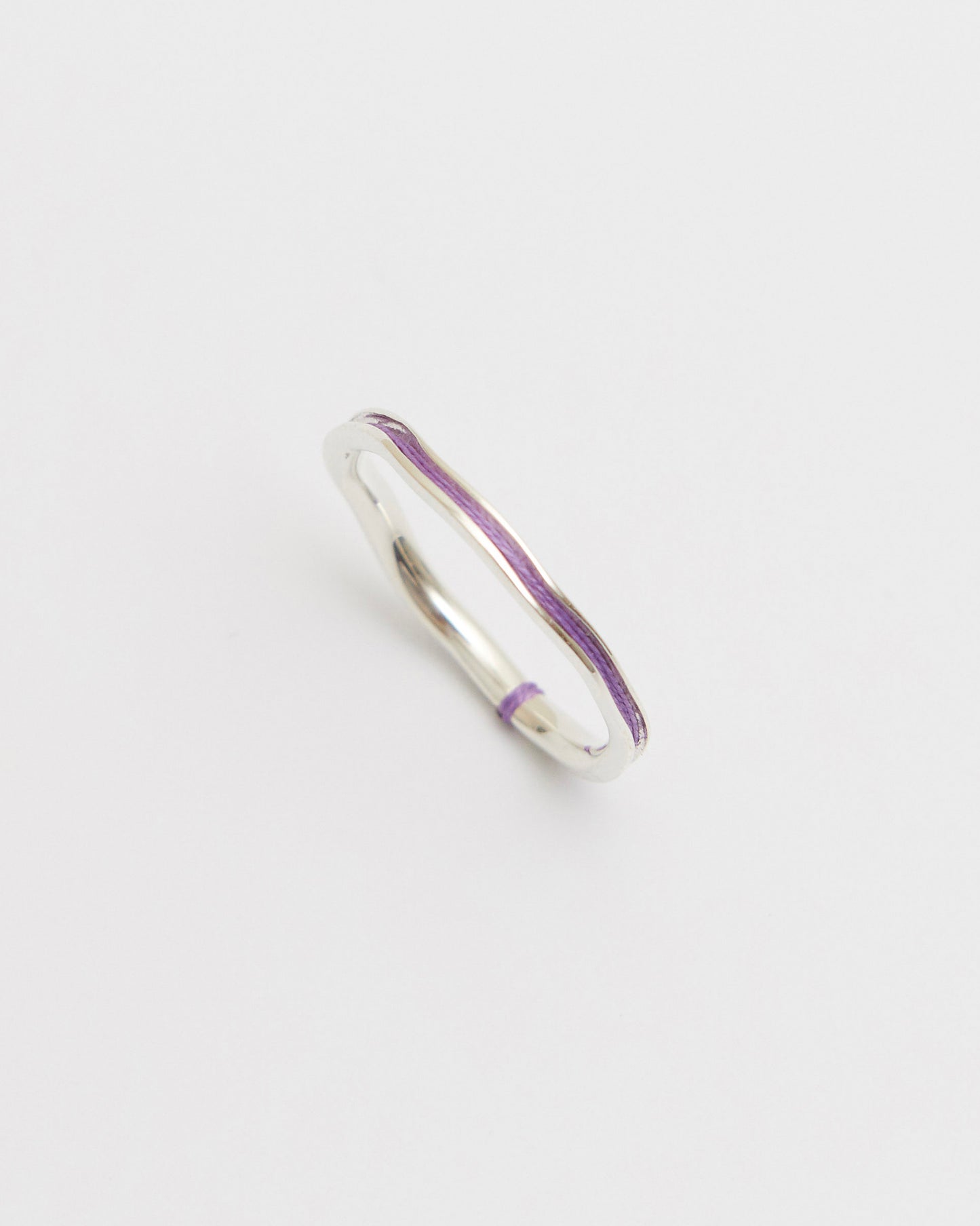 Silver ring with violet interior on a light gray background