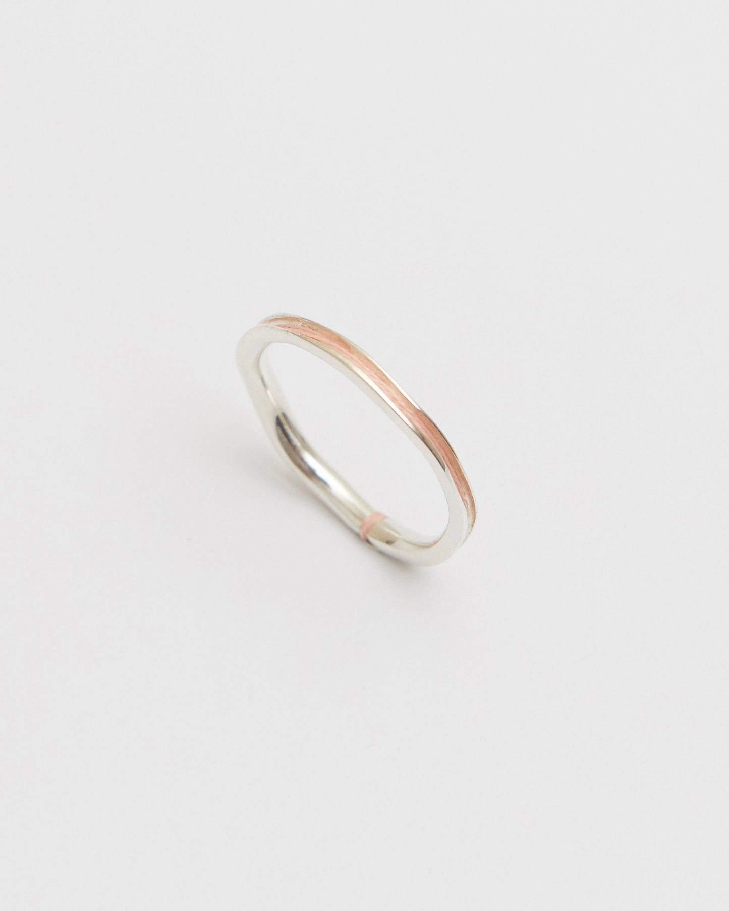 Silver ring with a peach accent on a light gray background