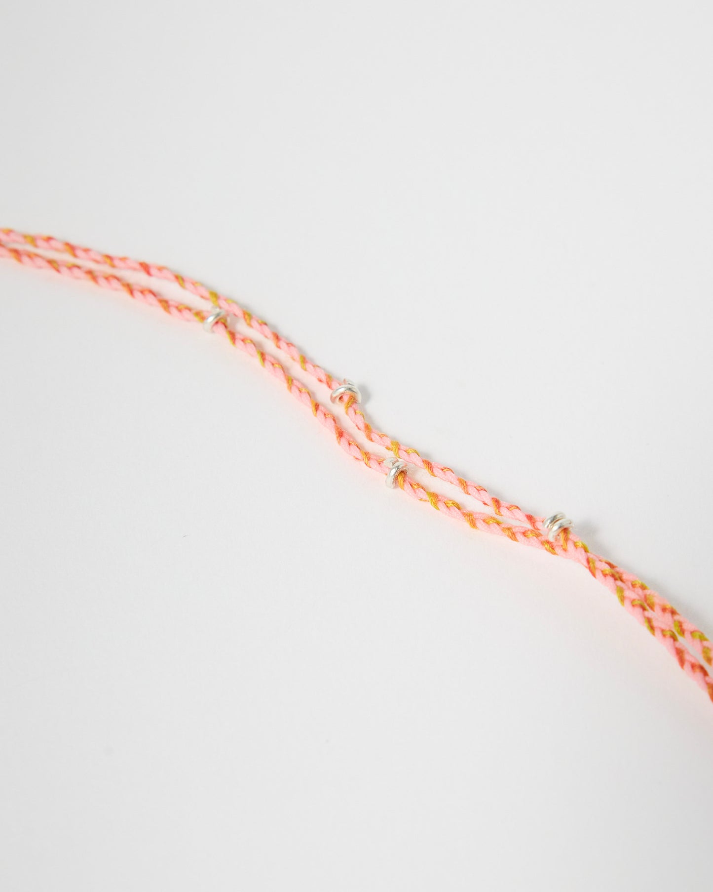 Detailed view of pink braided cord bracelet with silver wrap accents