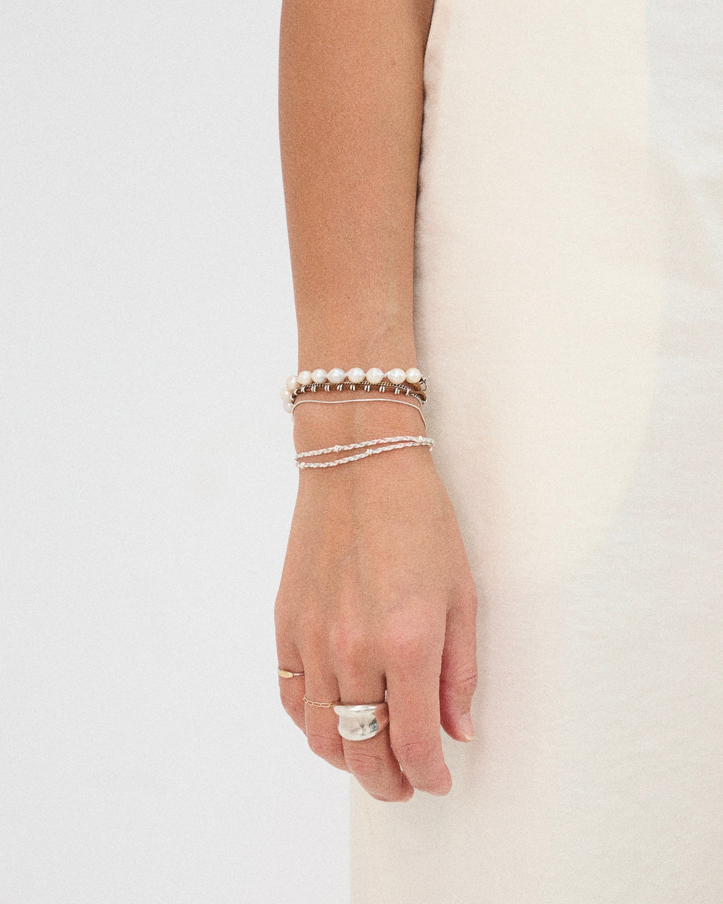Minimalist pastel woven bracelet styled with pearl jewelry and sterling silver accessories