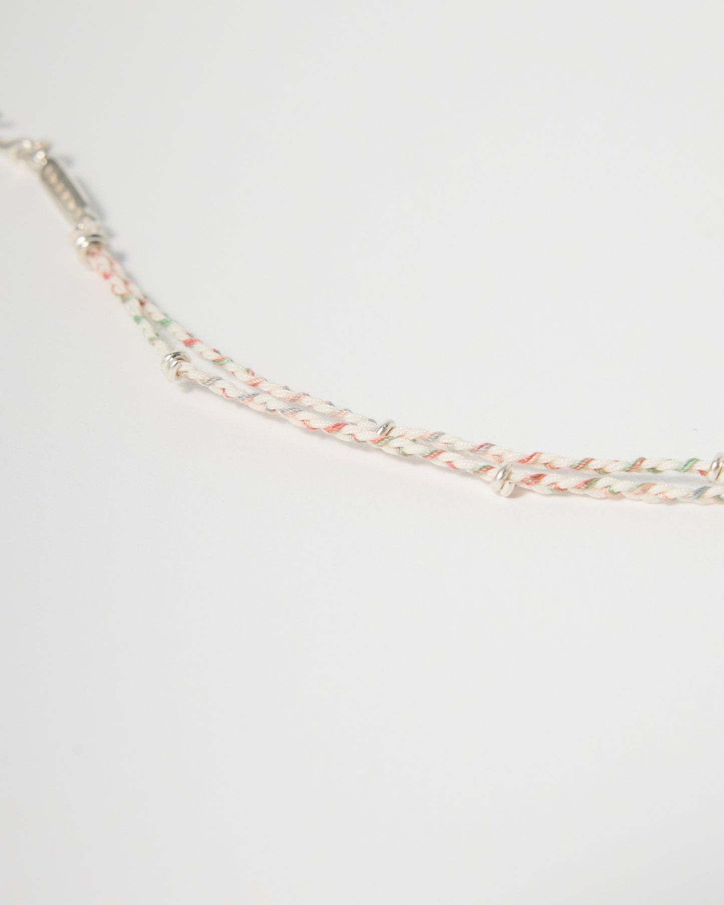 Close-up detail of woven pastel bracelet with sterling silver wraps and handcrafted braided cord design