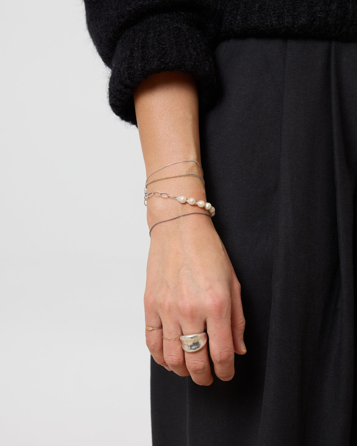 Model wearing an antique silver curb chain bracelet with a pearl bracelet stack – HANNA543 B1045 whisper curb chain