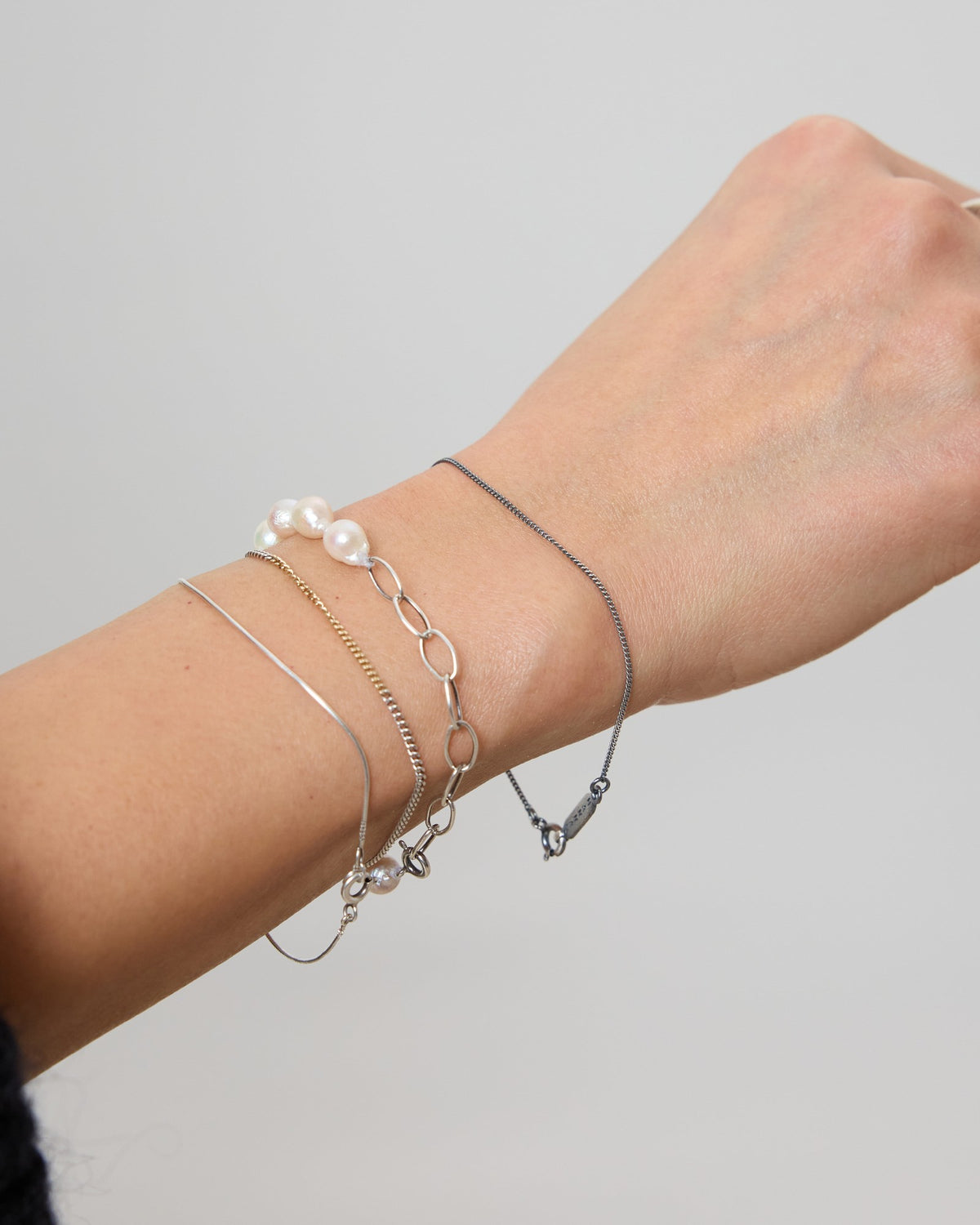 Wrist stacked with an antique silver curb chain, pearl and link bracelets – HANNA543 B1045 whisper curb chain