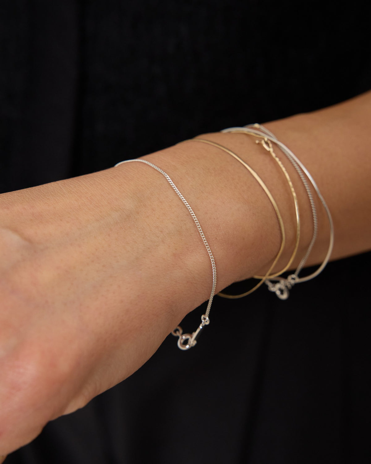 Wrist wearing a fine silver curb chain bracelet in a mixed bracelet stack – HANNA543 B1045 whisper curb chain