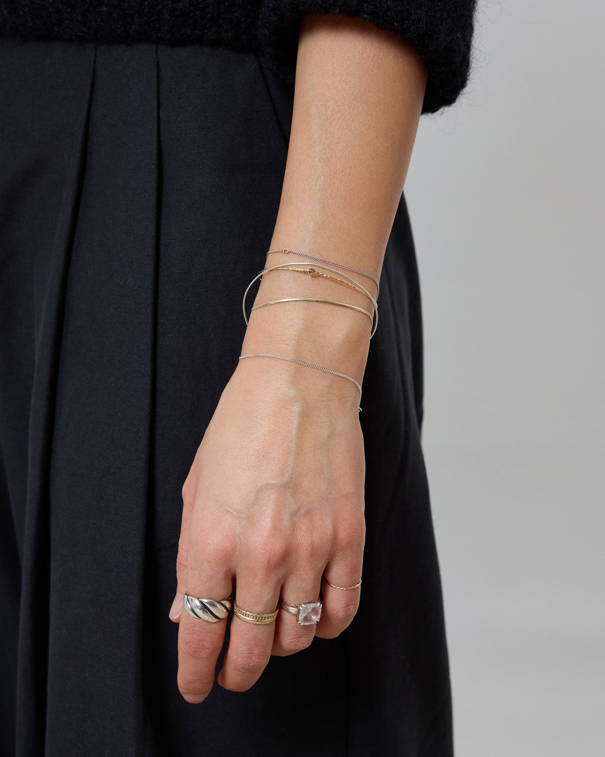 Model wearing a stack of fine silver and gold chain bracelets with rings – HANNA543 B1045 whisper curb chain