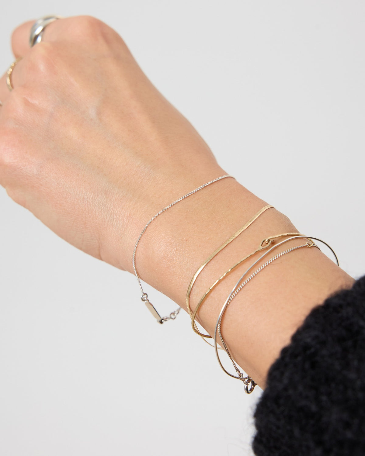 Wrist stacked with a dainty silver curb chain and gold bracelets – HANNA543 B1045 whisper curb chain