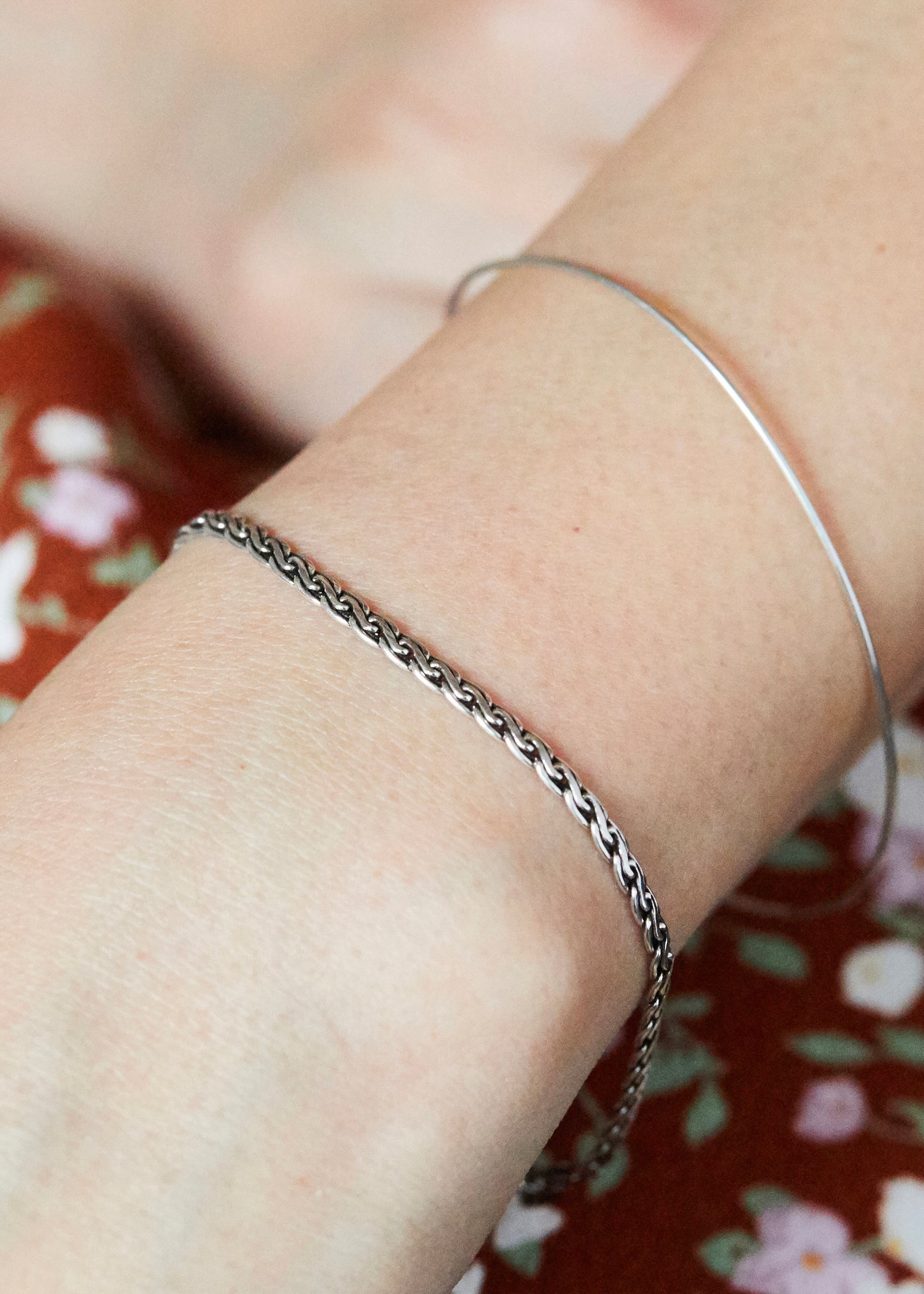 Minimal sterling silver woven chain bracelet worn on wrist, styled with layered silver jewelry for a modern everyday minimalist aesthetic.