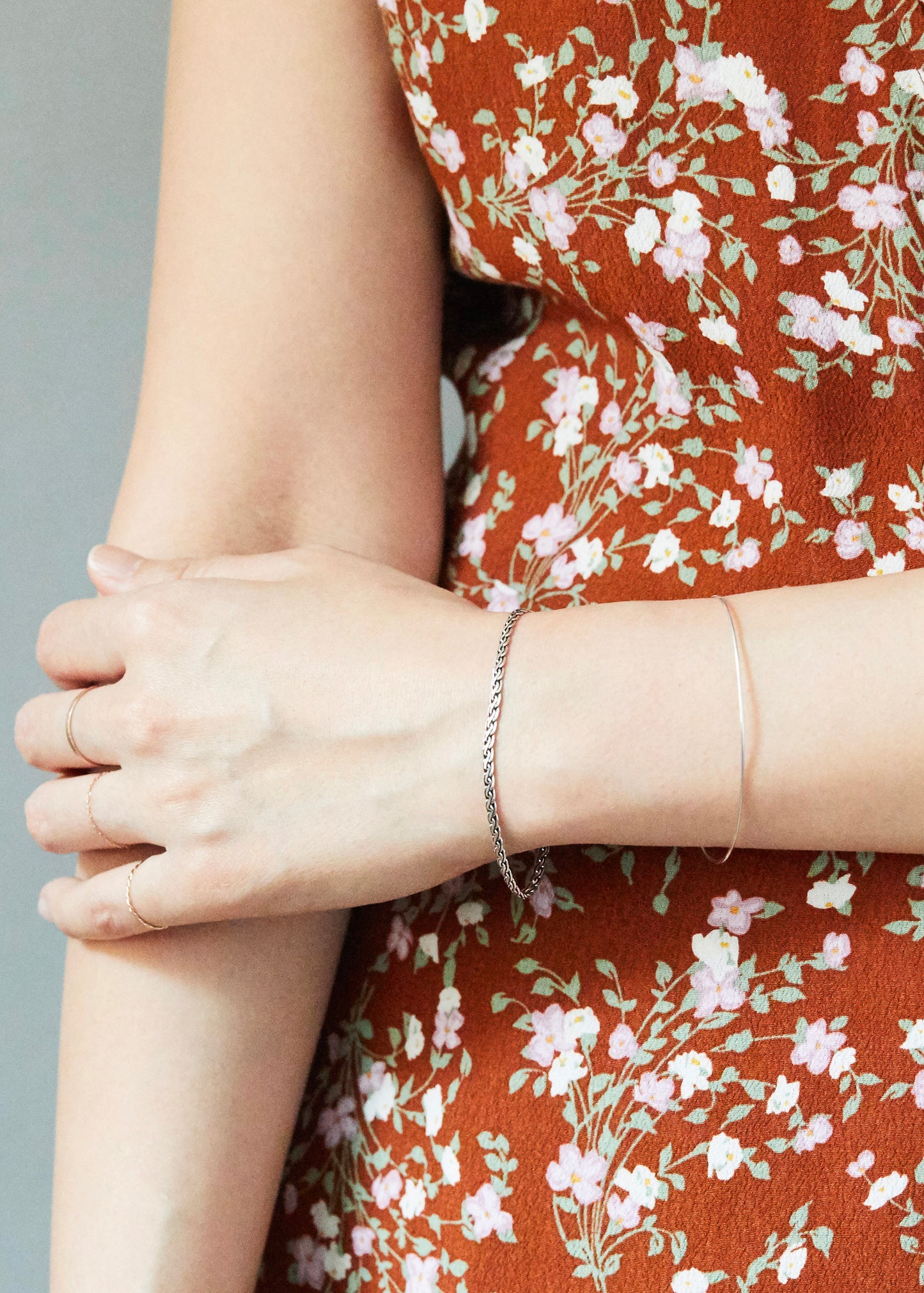 Minimal sterling silver bracelet worn with floral dress and layered jewelry, styled for soft everyday fashion and understated elegance.