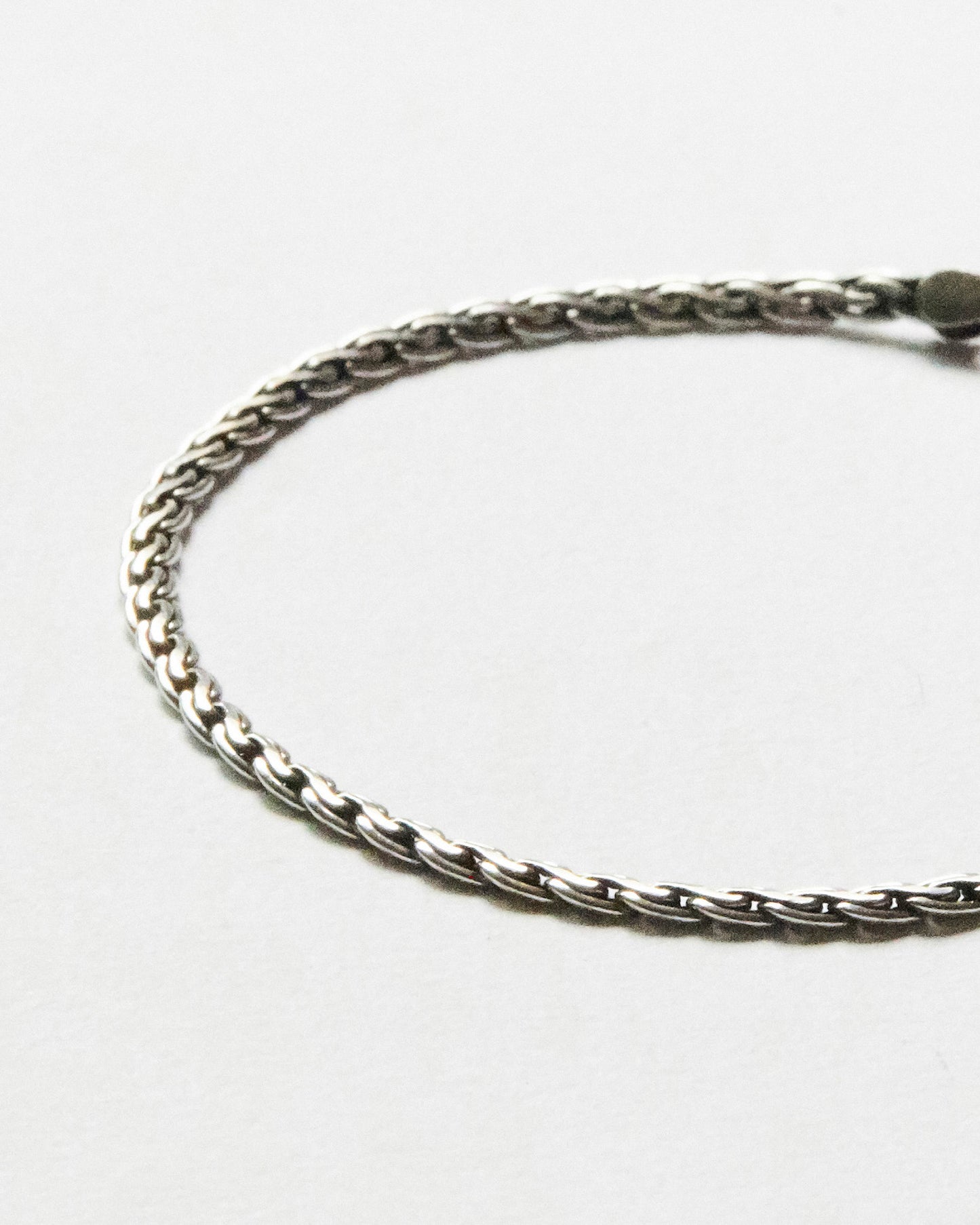 Macro close-up of sterling silver woven chain bracelet showcasing detailed interlocking links and polished handcrafted finish.