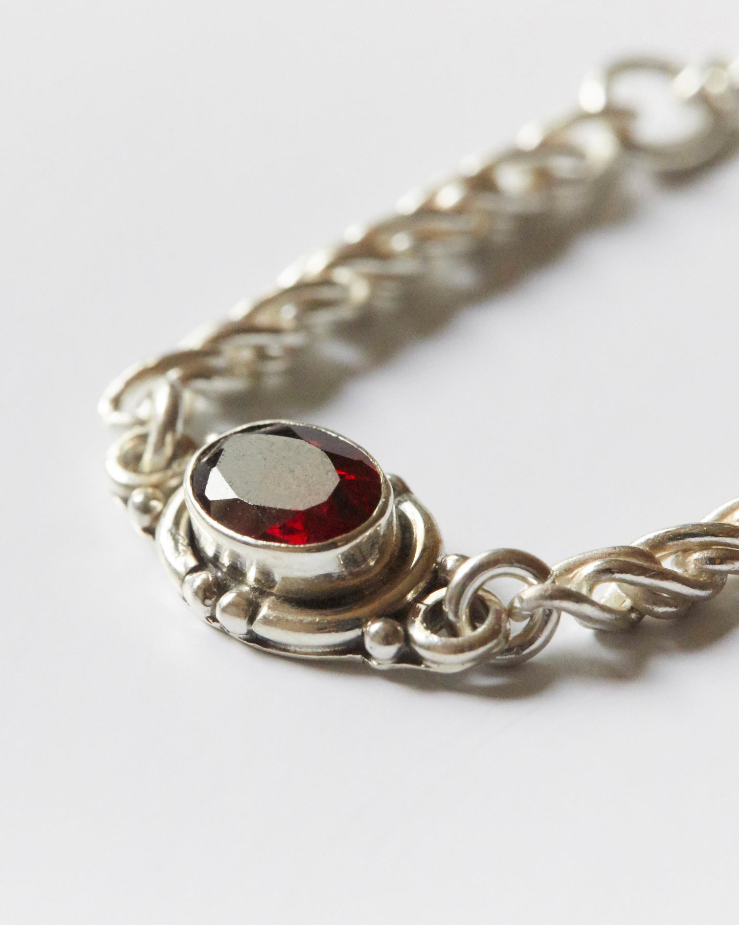 close-up of red gemstone set in silver chain bracelet showing texture and detail