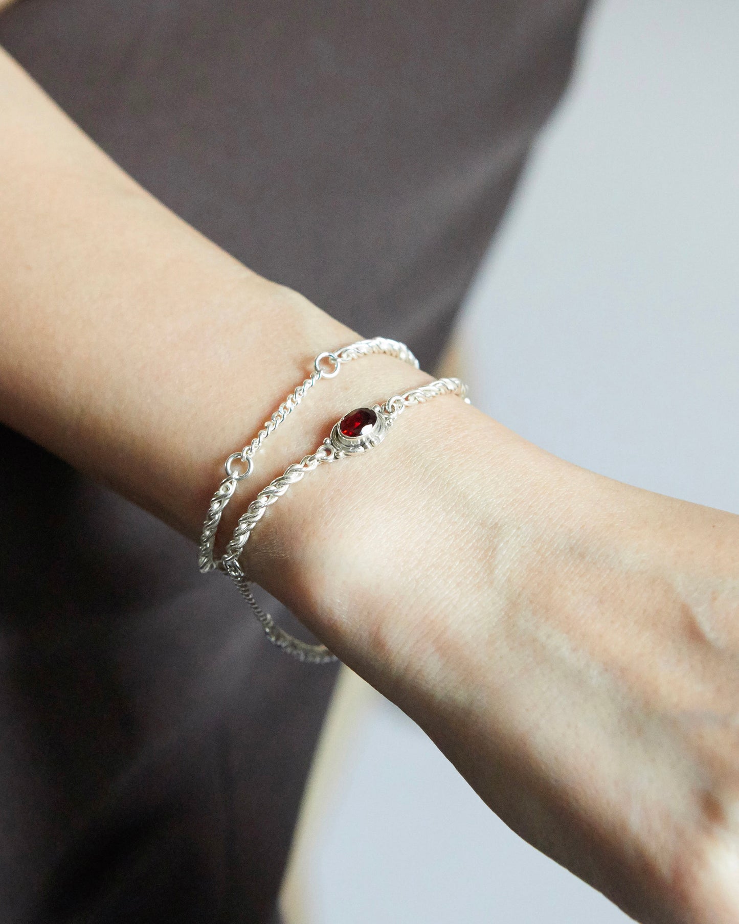silver chain bracelet with red stone styled on wrist with soft shadow