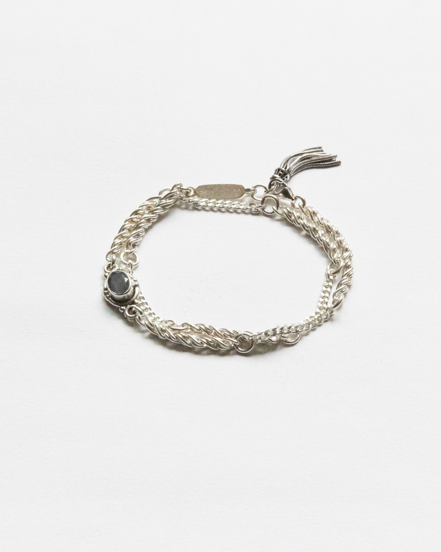 silver bracelet with twisted chain texture and grey gemstone detail on white background