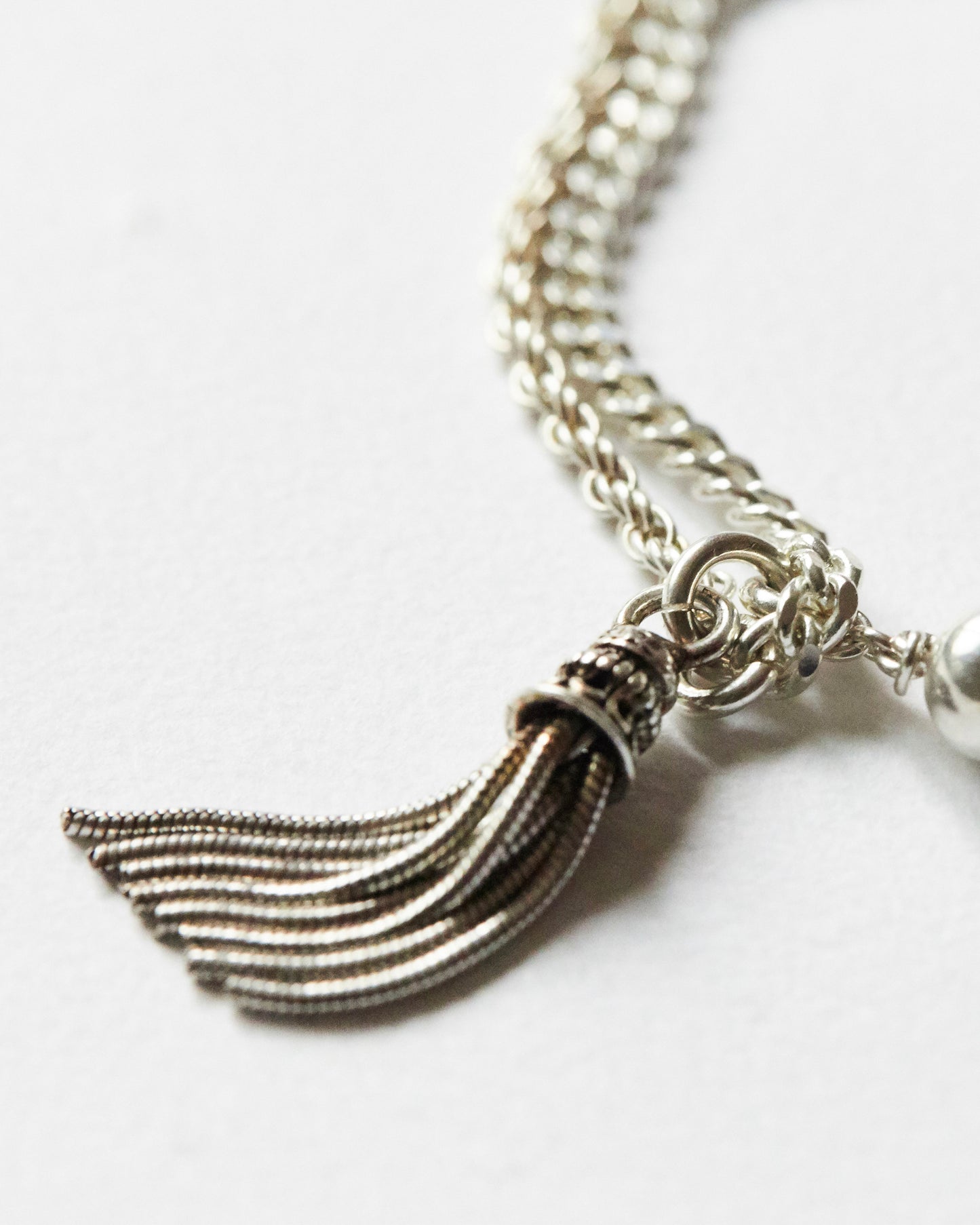 close-up of silver tassel and bead detail on chain bracelet