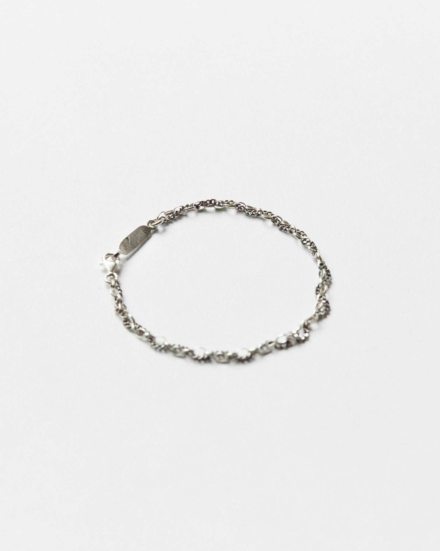 Minimal sterling silver mixed-link bracelet on white background