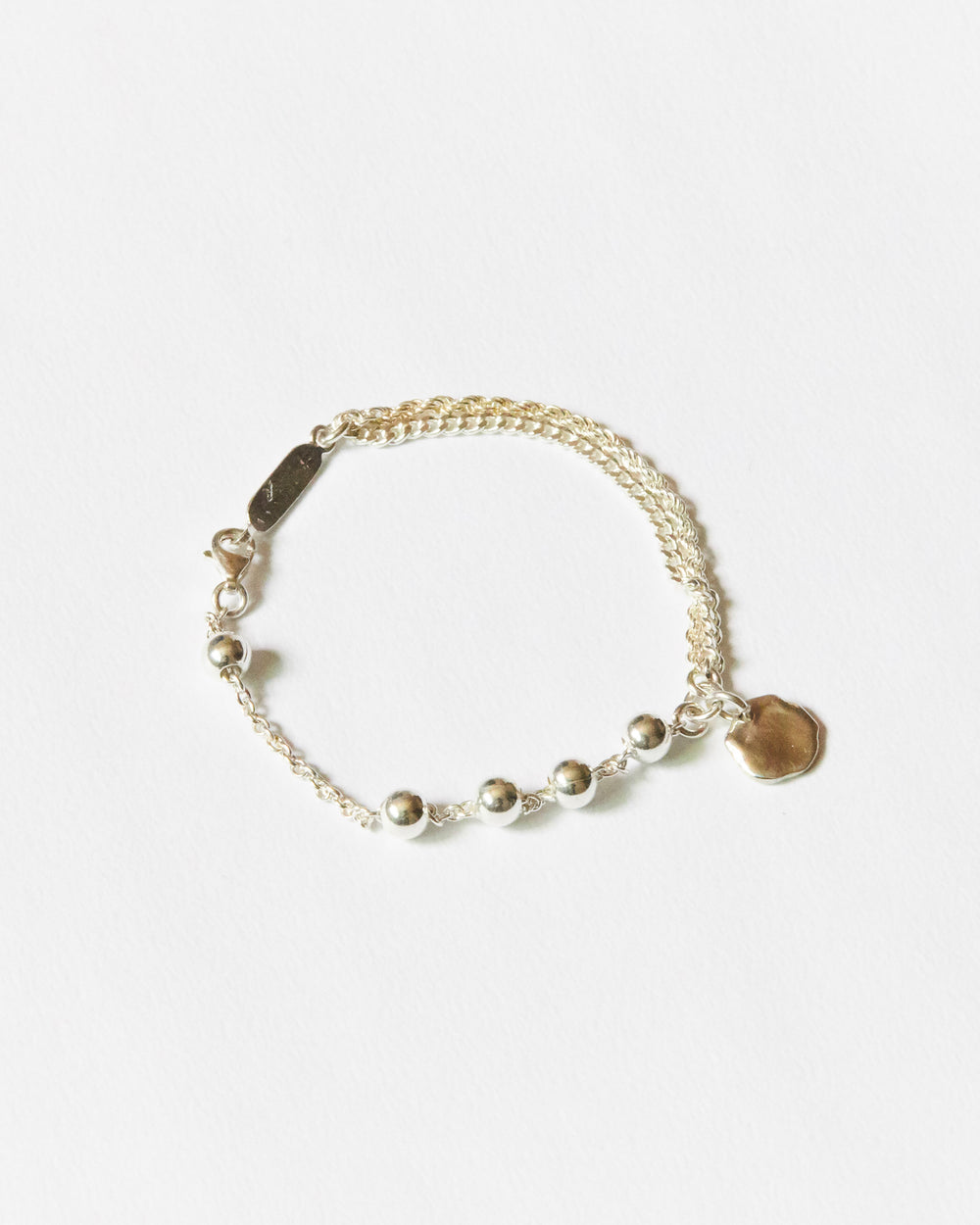 silver chain bracelet flat lay with bead detail and organic charm minimalist modern jewelry product shot