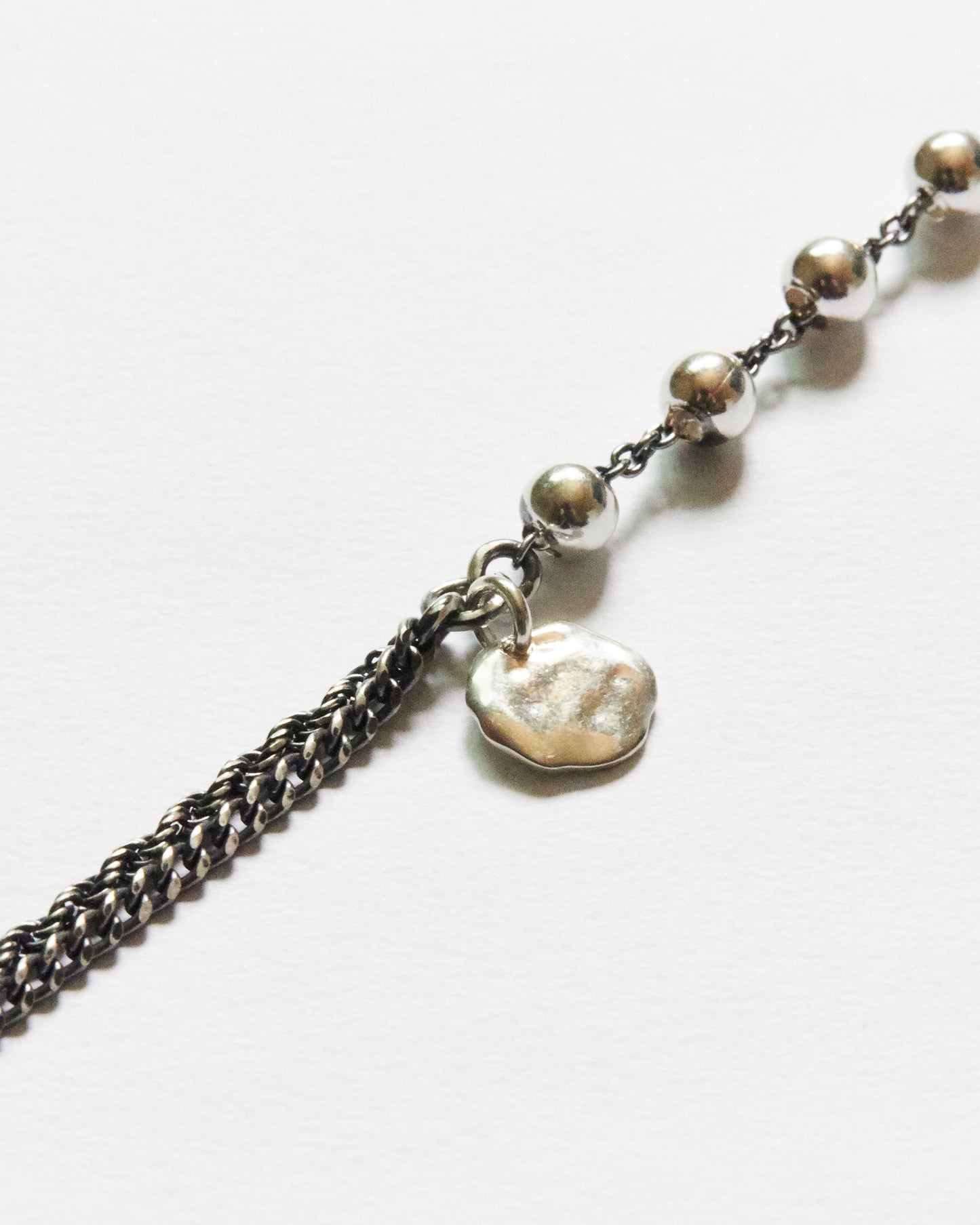 macro detail of antique silver bead chain and organic charm bracelet premium minimal jewelry texture