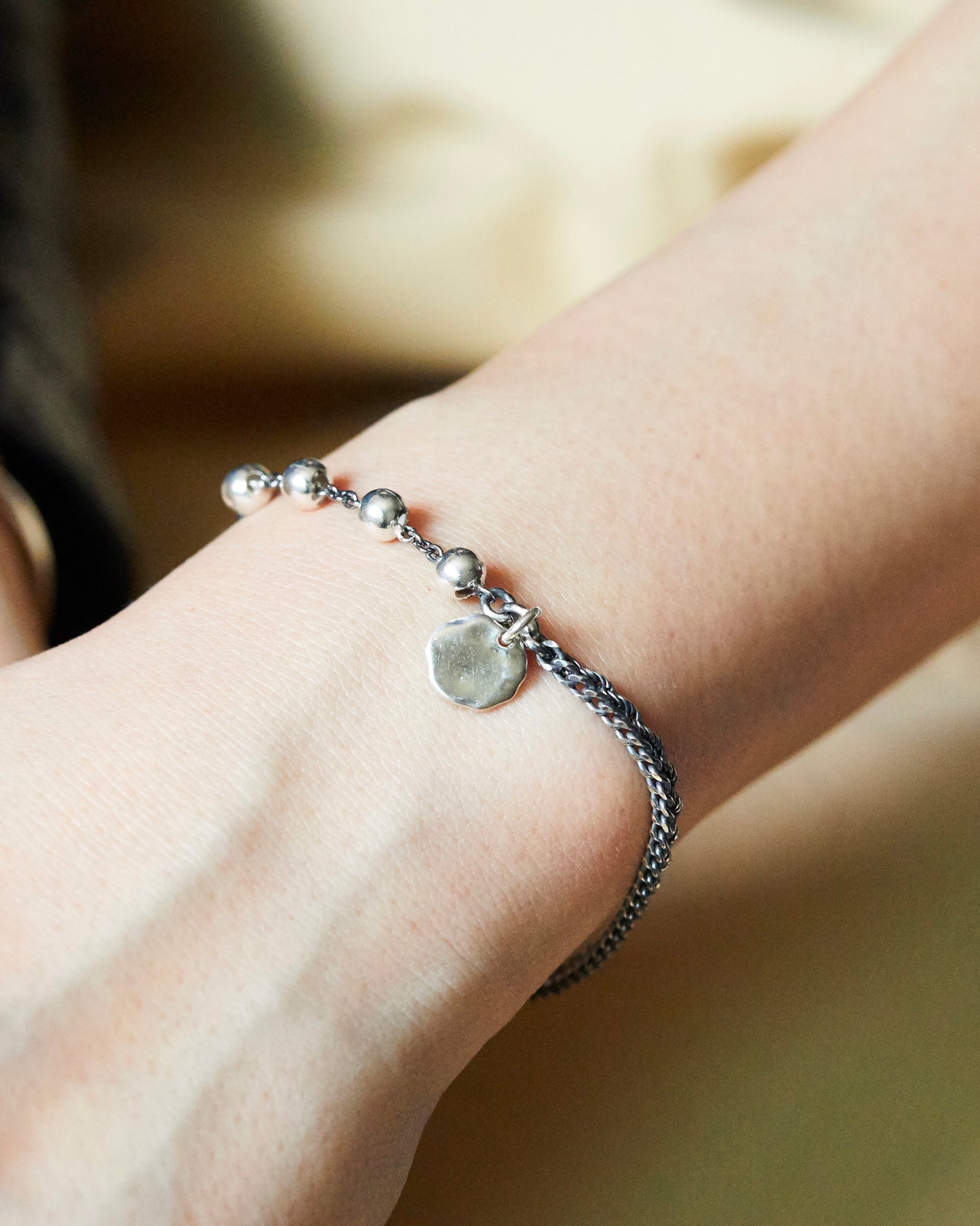 antique silver anklet with beads on a person's ankle against a neutral background