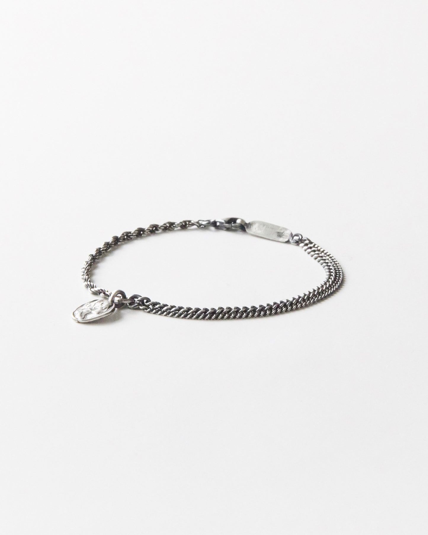 925 silver bracelet with dual chain detail and textured coin pendant on white background