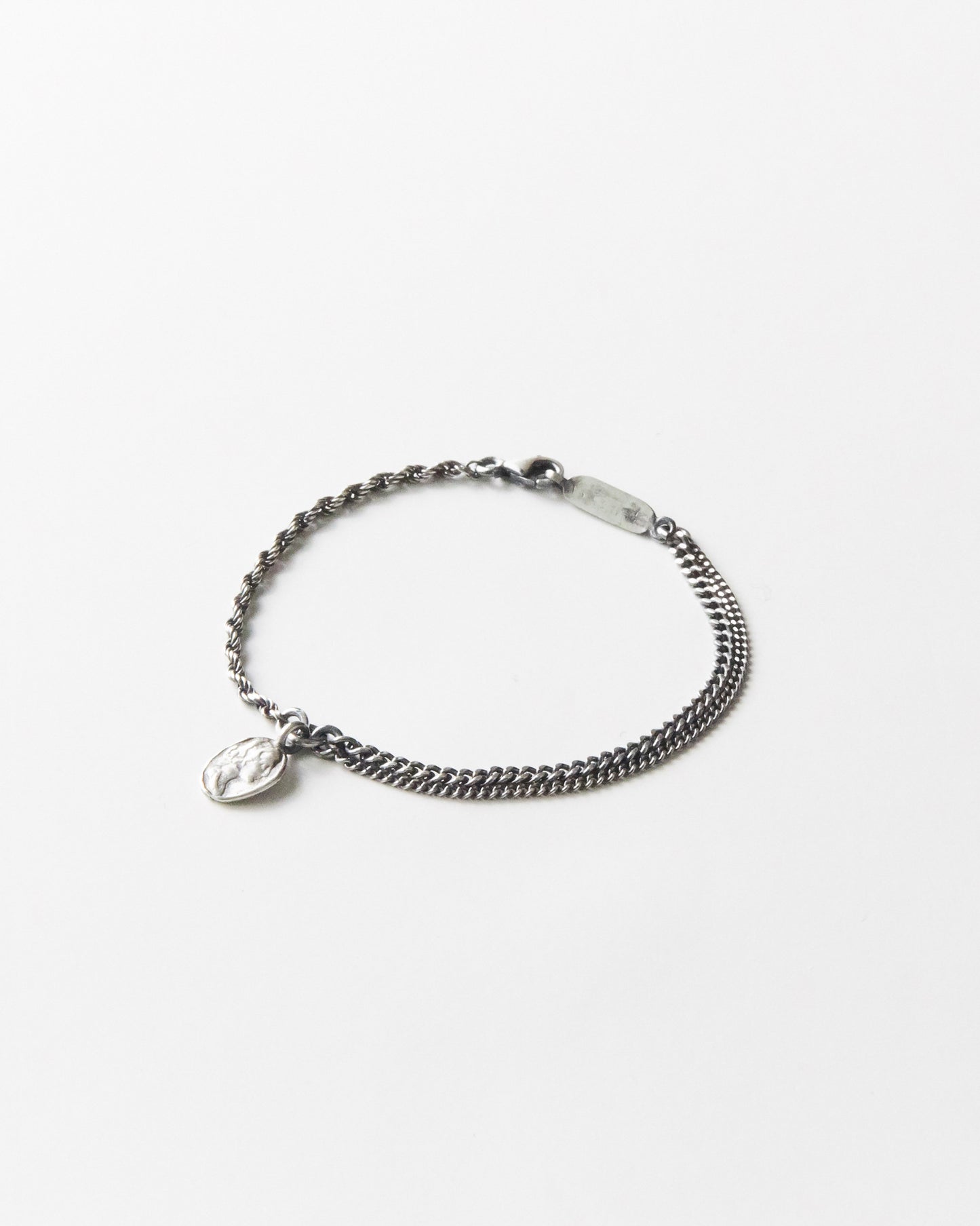 Flat lay of B507 925 silver bracelet with hammered medallion pendant, white background