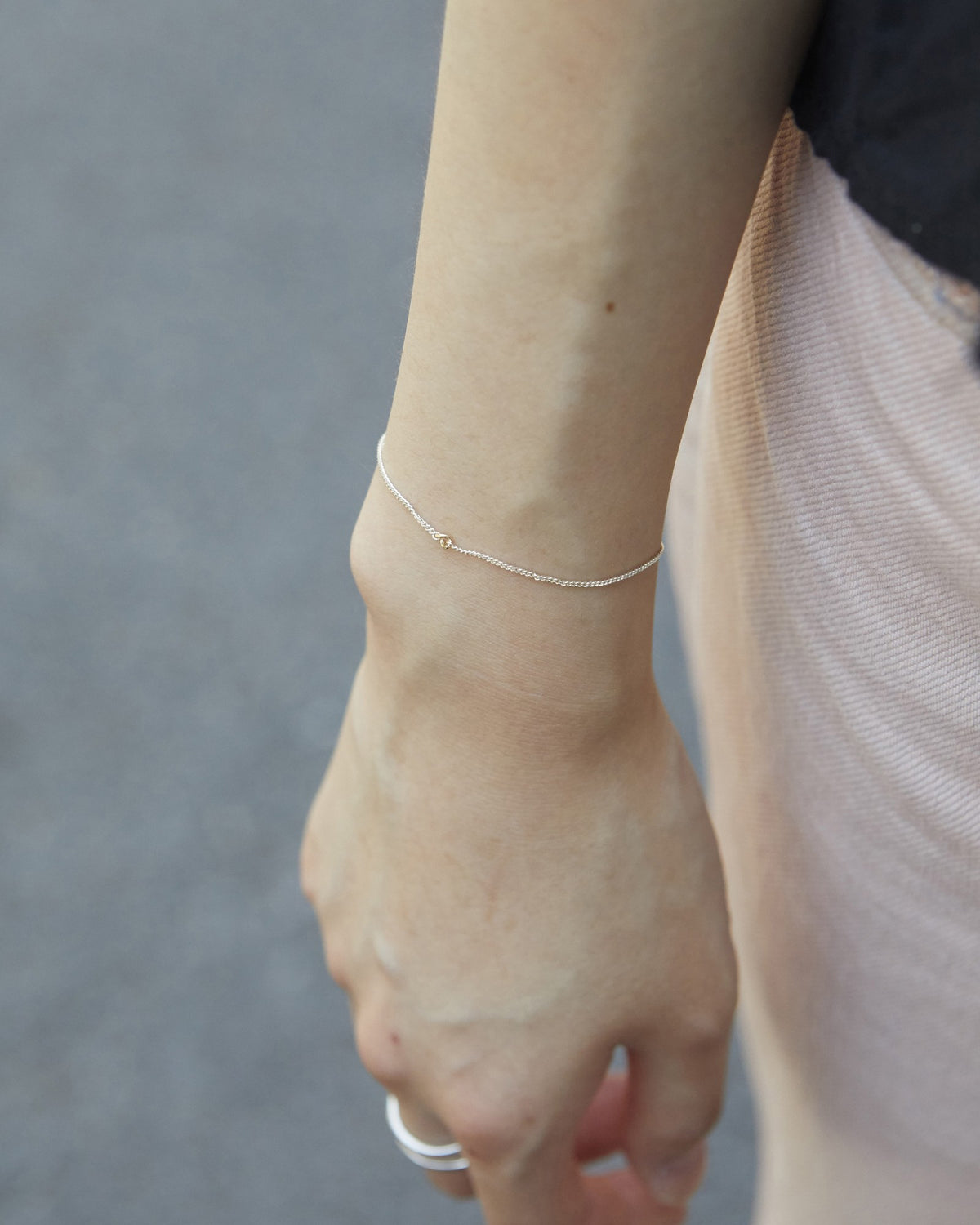 Delicate silver and 14K gold chain bracelet worn on the wrist, casual outfit – HANNA543 B535 gold note chain