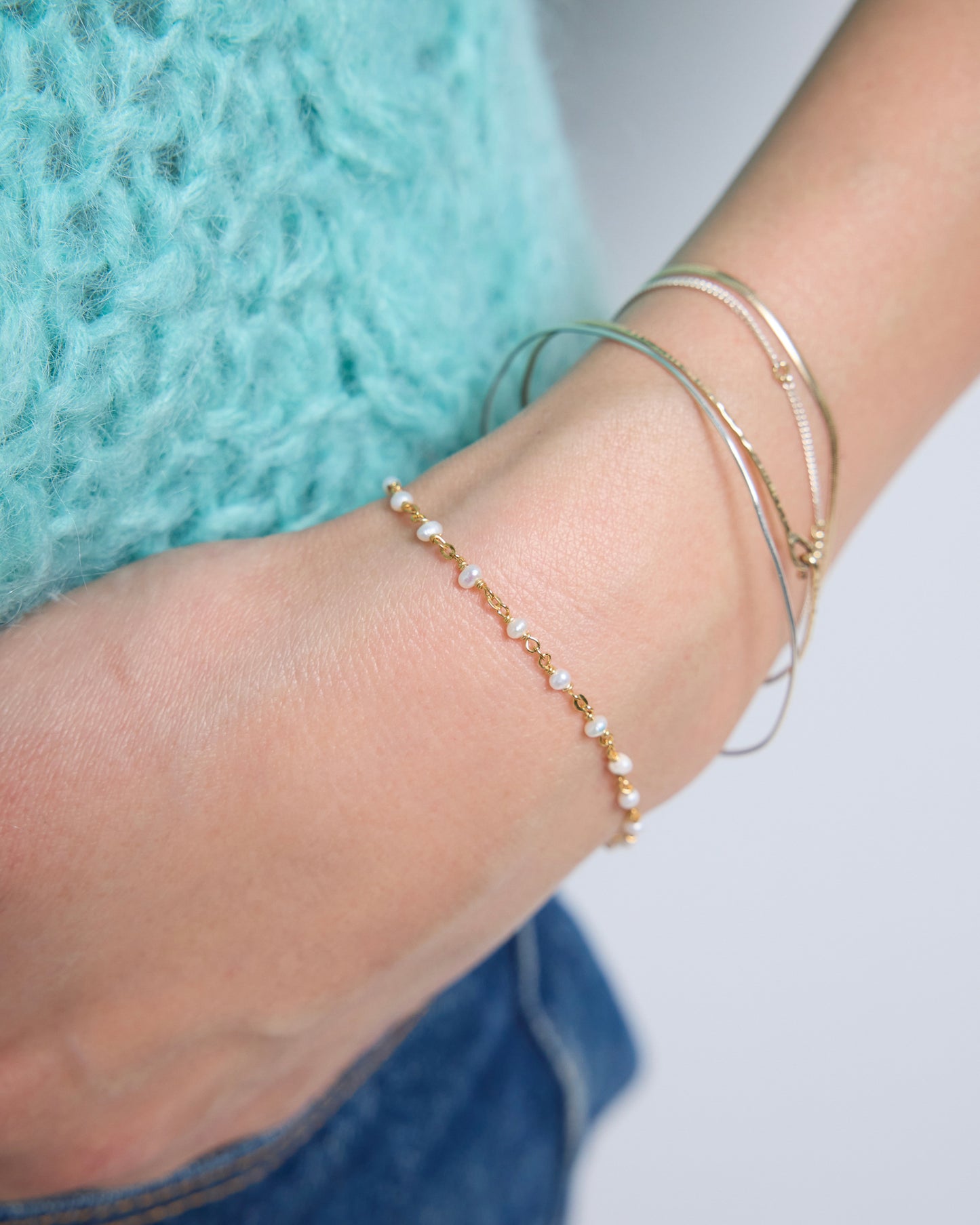 Close-up of delicate gold pearl bracelet styled on wrist