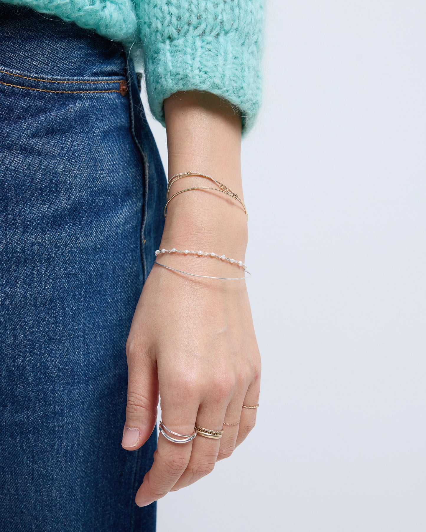 Delicate pearl bracelet styled with rings and layered bracelets