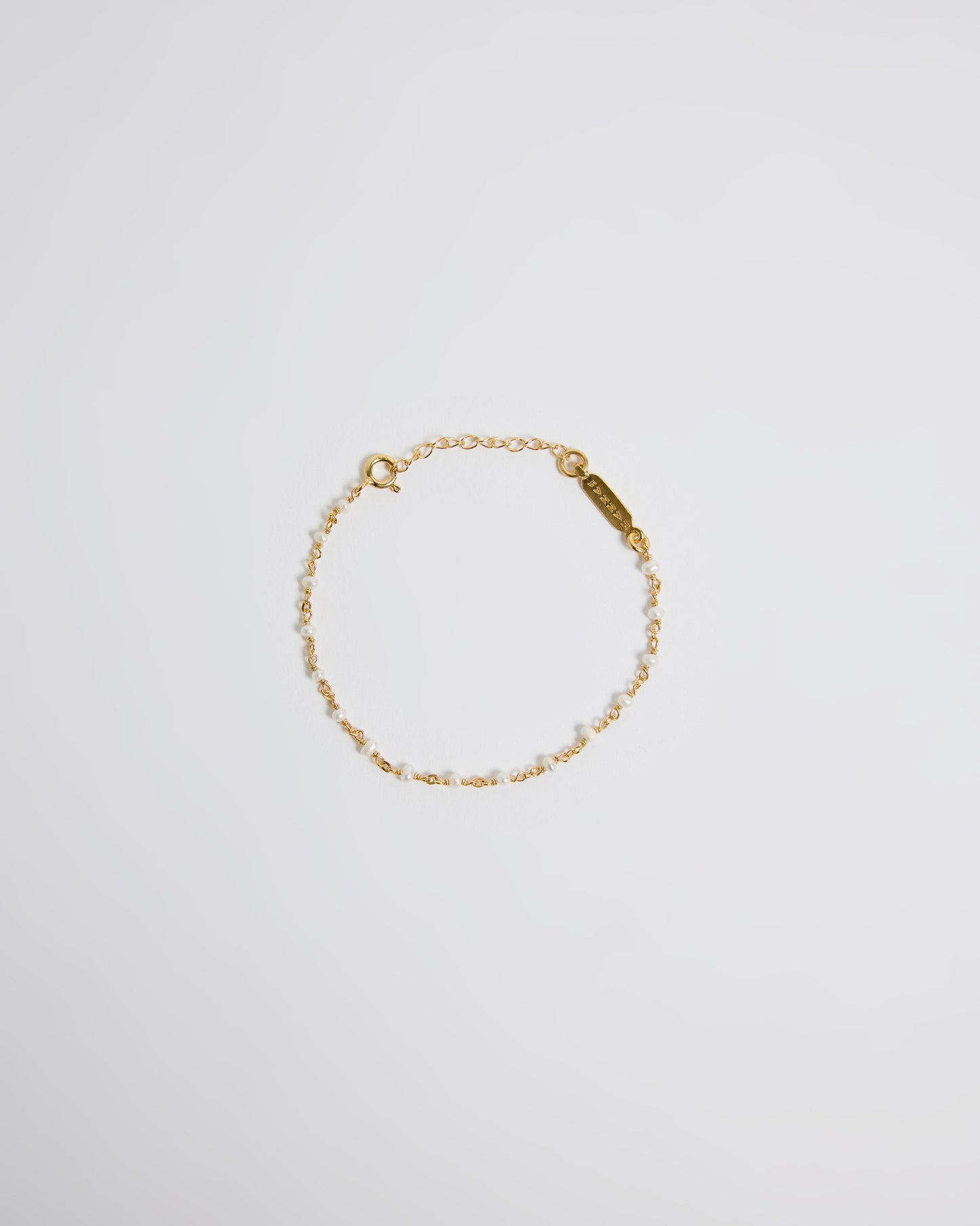 Top view of delicate gold chain bracelet with tiny pearls