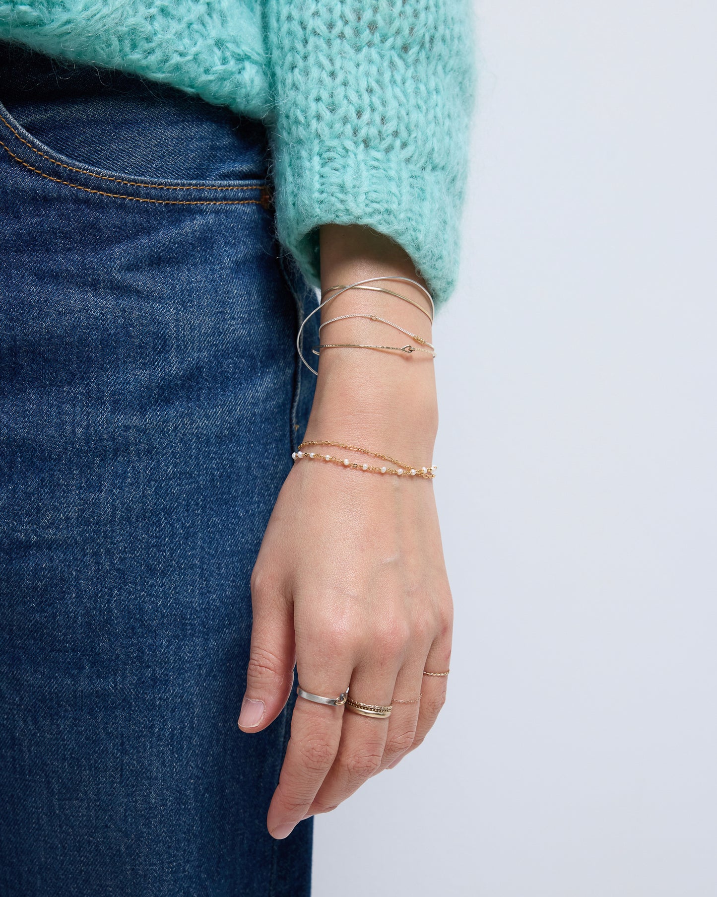 Minimal layered gold pearl bracelet styled with rings and knit sweater, feminine everyday jewelry