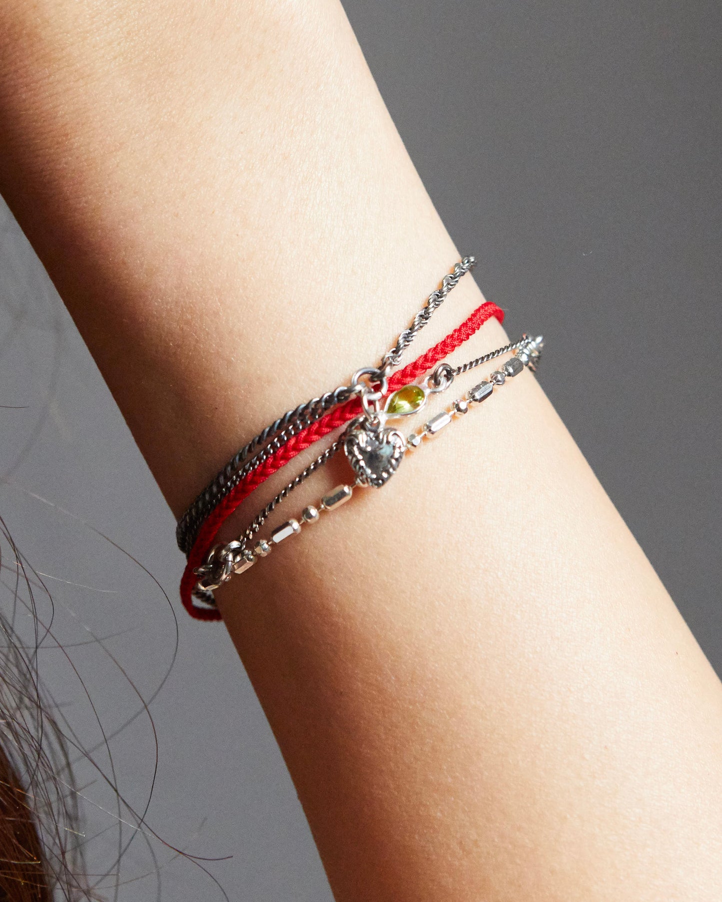 Silver heart charm bracelet styled with blue and silver thread bracelets for a casual look