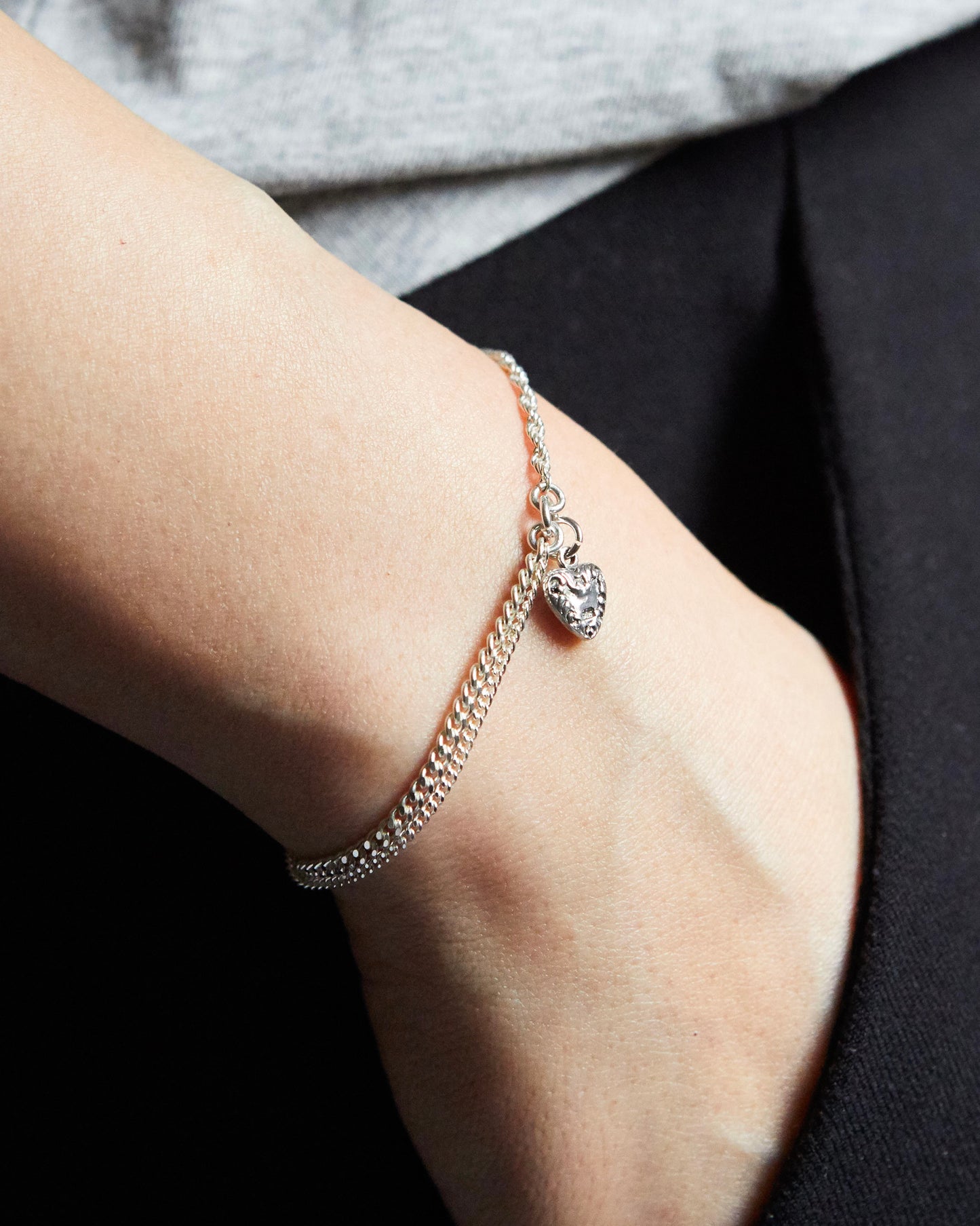 Close-up of a person's wrist wearing a delicate bracelet with a heart charm.
