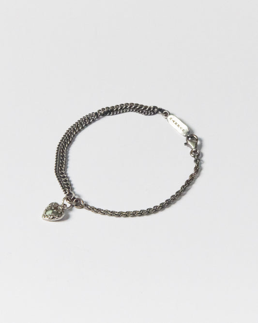Flat lay of handcrafted silver bracelet with twisted and curb chains, featuring heart charm