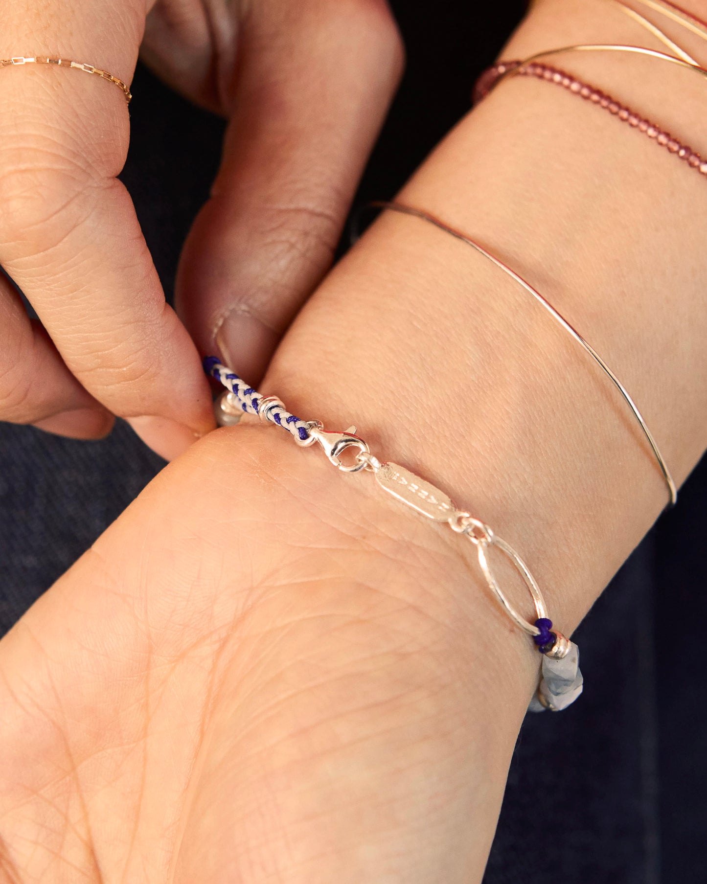 Bracelet worn on wrist with red sleeve, silver accents glint subtly