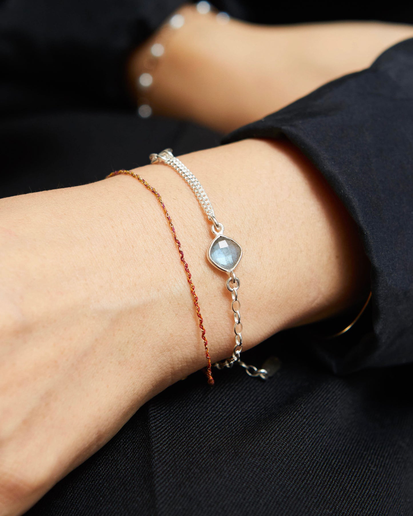 Close-up of a wrist wearing two bracelets with a dark background