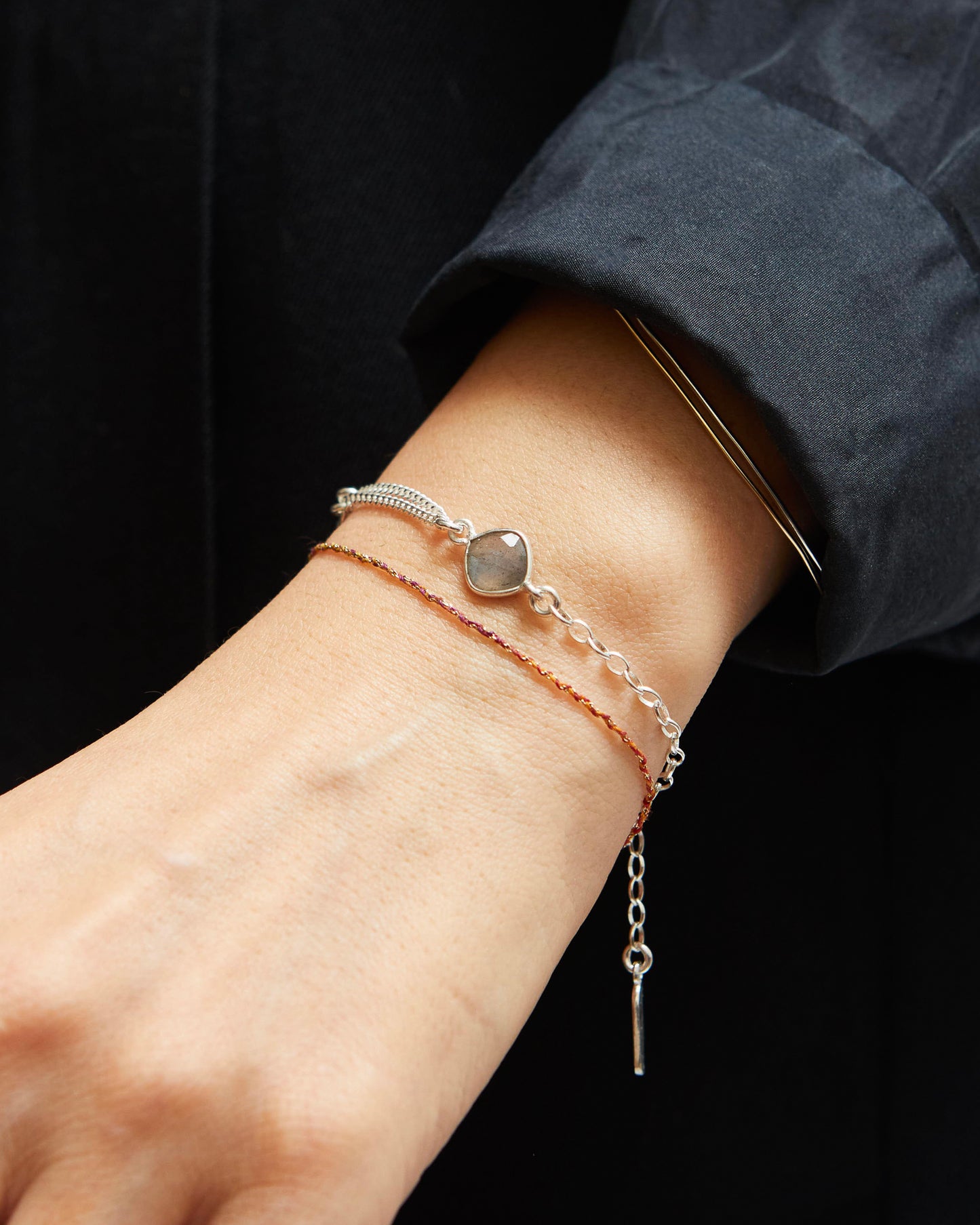 Close-up of a wrist wearing multiple bracelets with a dark background