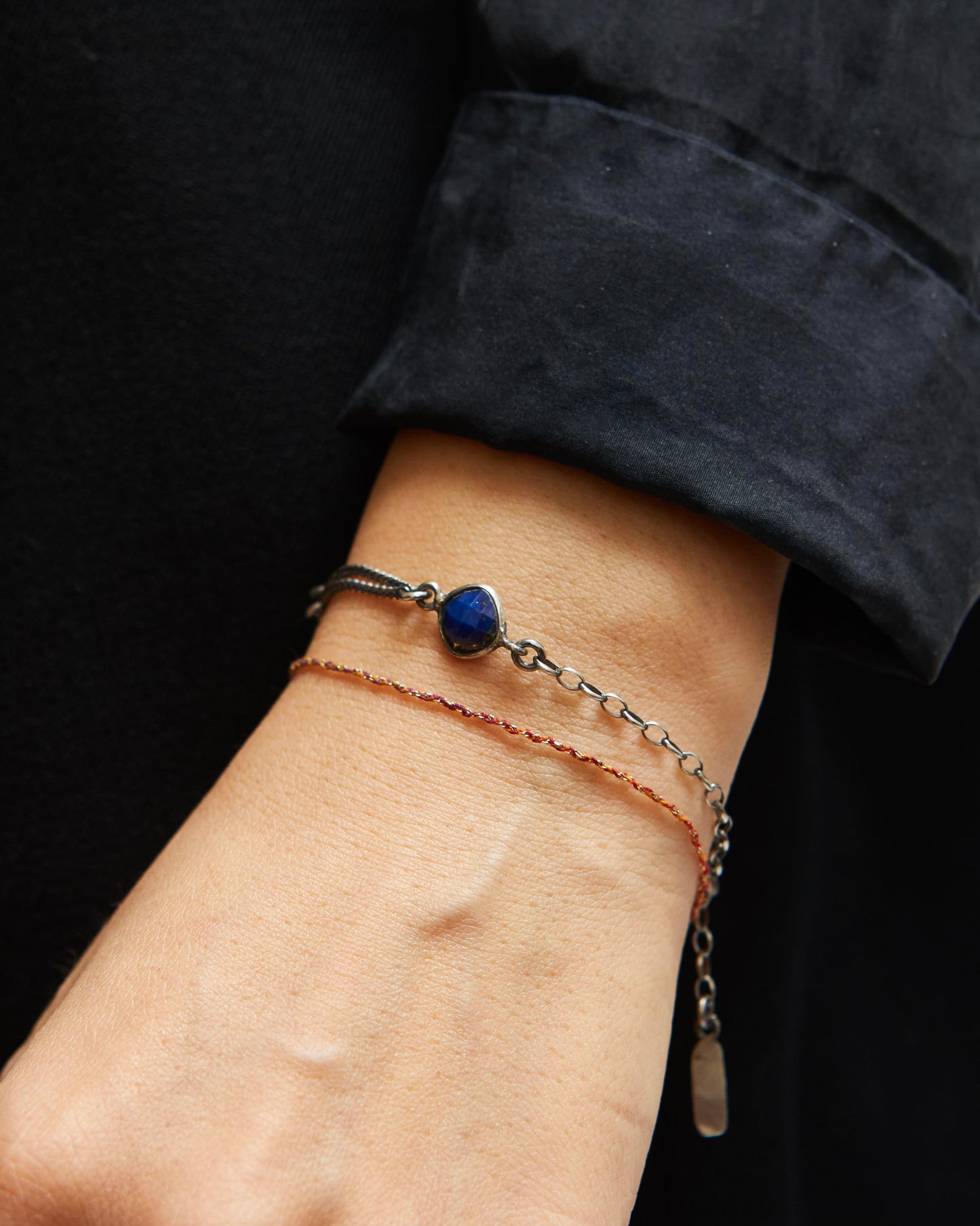 Close-up of a wrist wearing two bracelets with a dark background