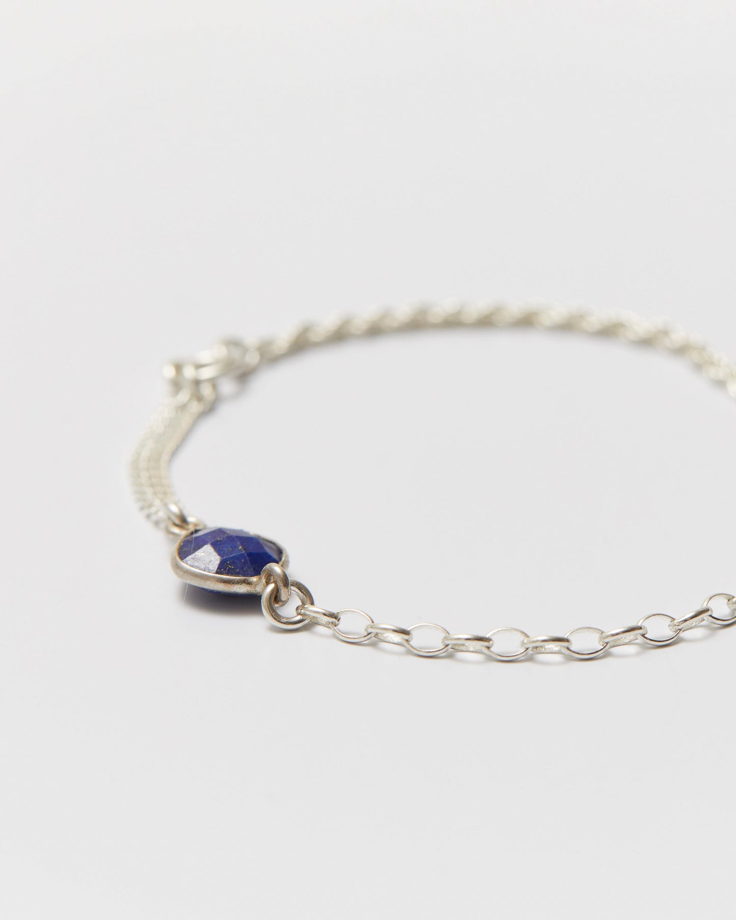 Silver bracelet with a blue gemstone on a light gray background