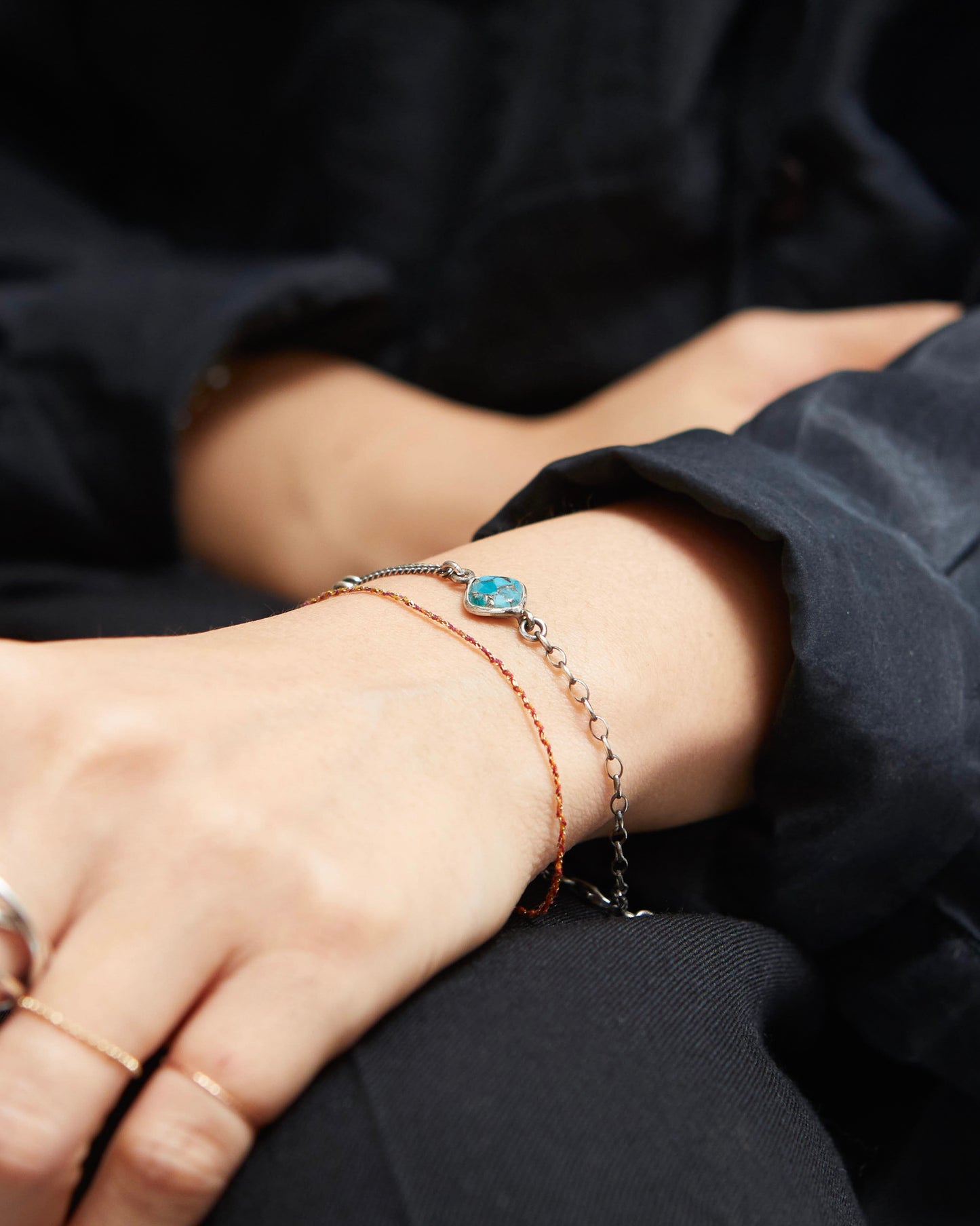 Close-up of a person's wrist wearing multiple bracelets with a dark background