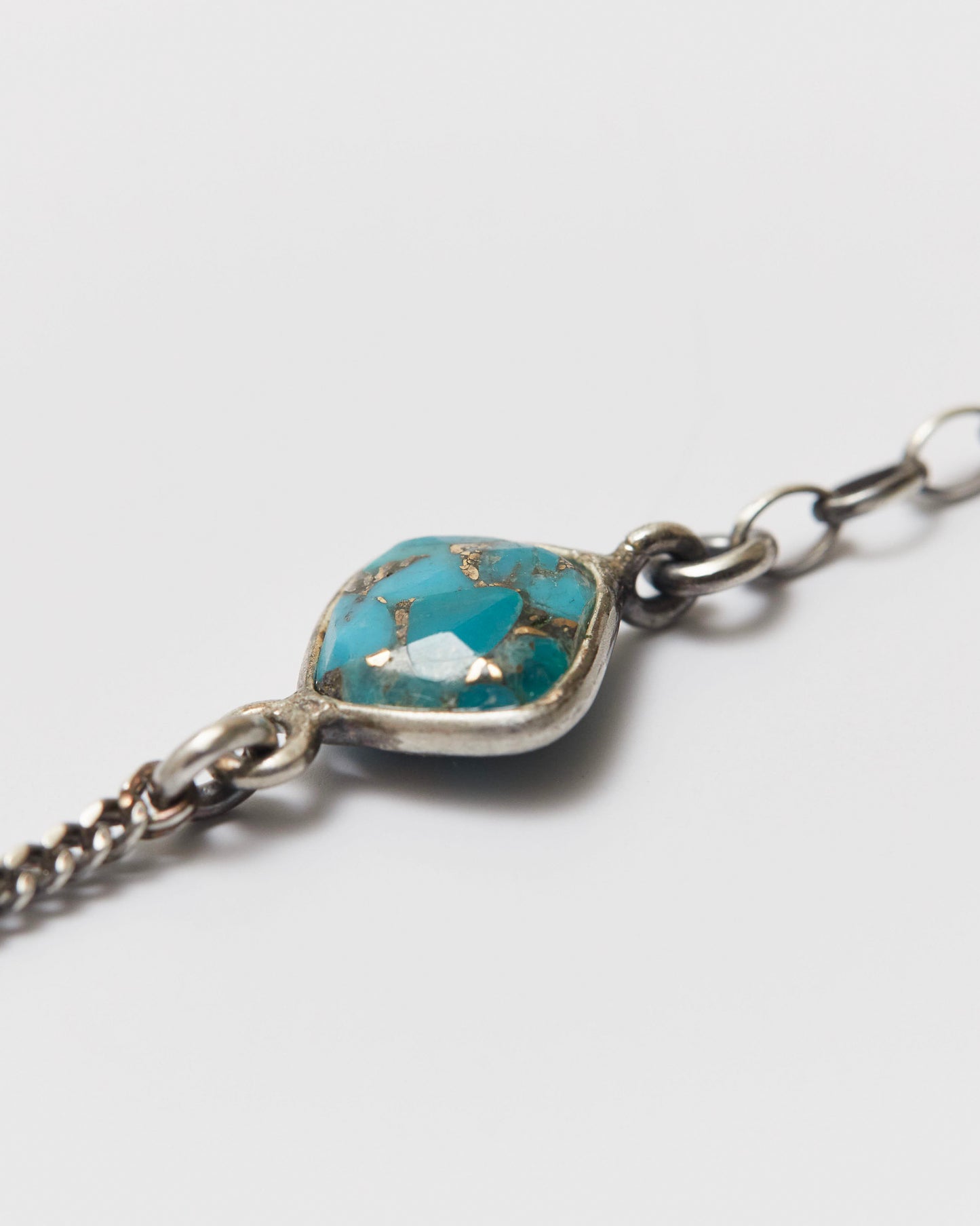 Bracelet with turquoise stone and antique silver chain on a light gray background