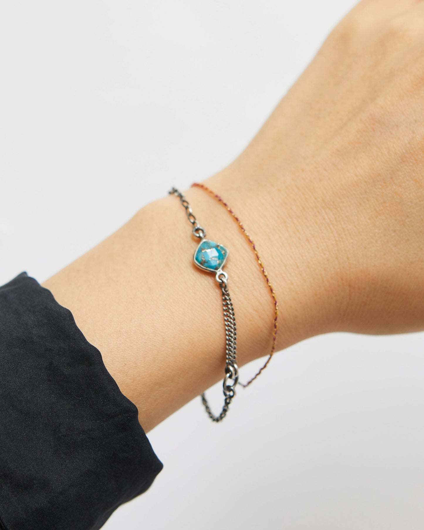 Bracelet with a blue heart-shaped gemstone on a wrist against a white background
