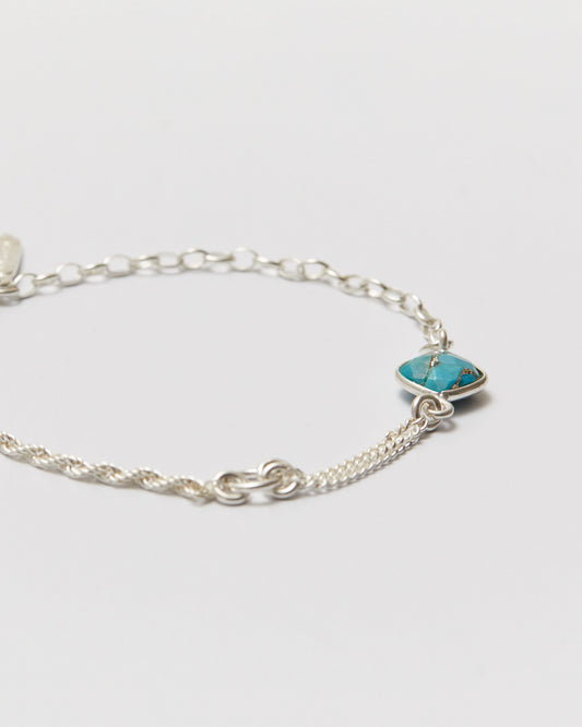 Silver bracelet with a turquoise stone on a light gray background