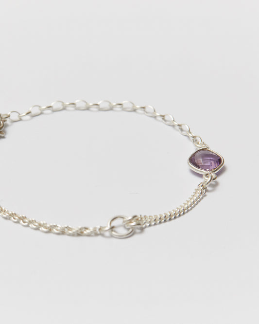 Silver bracelet with a purple gemstone on a light gray background