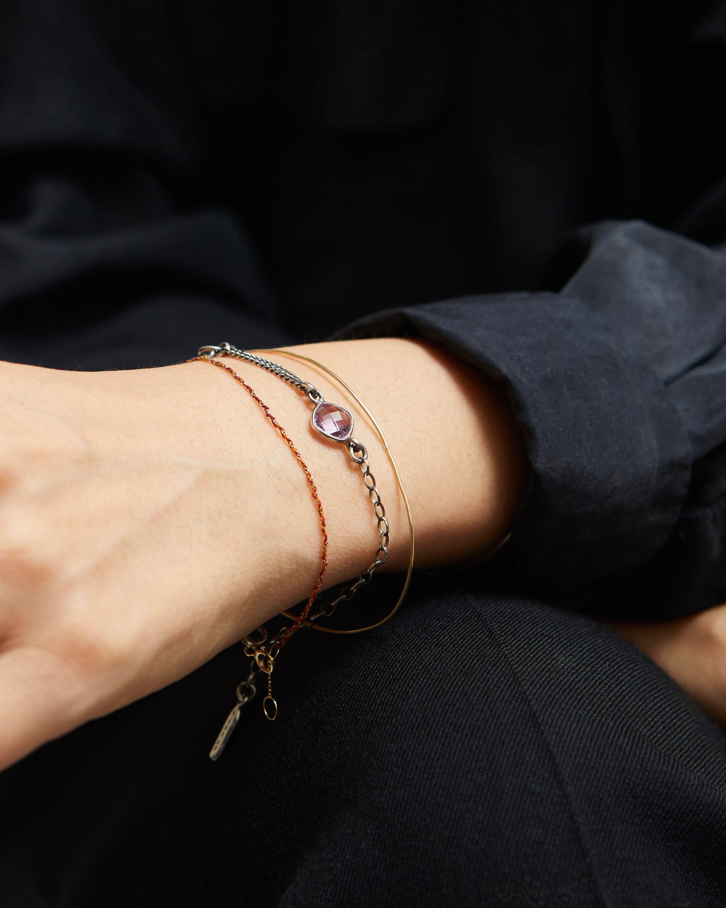 Close-up of a wrist wearing multiple bracelets with a dark background
