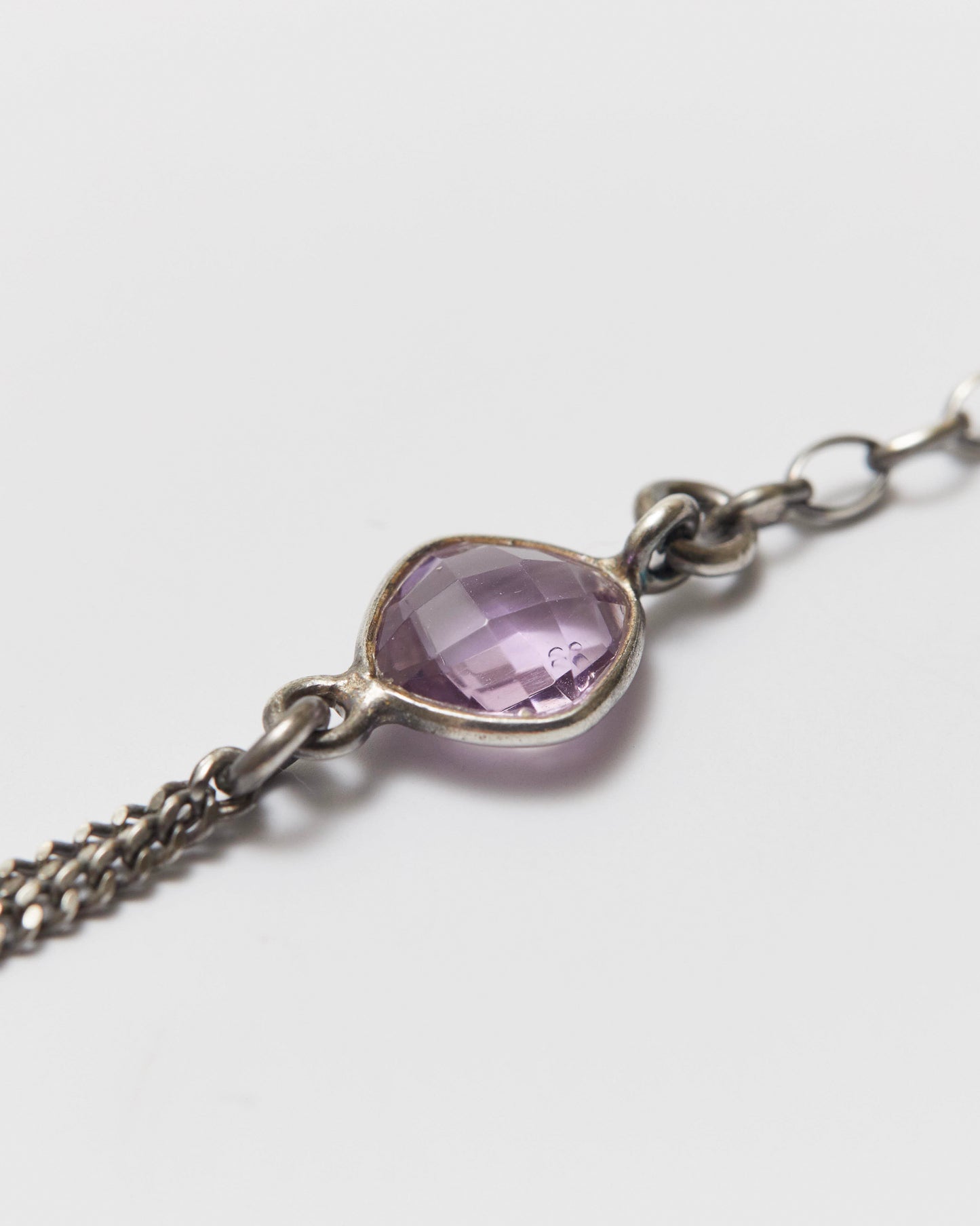 antique silver bracelet with a purple gemstone on a light gray background