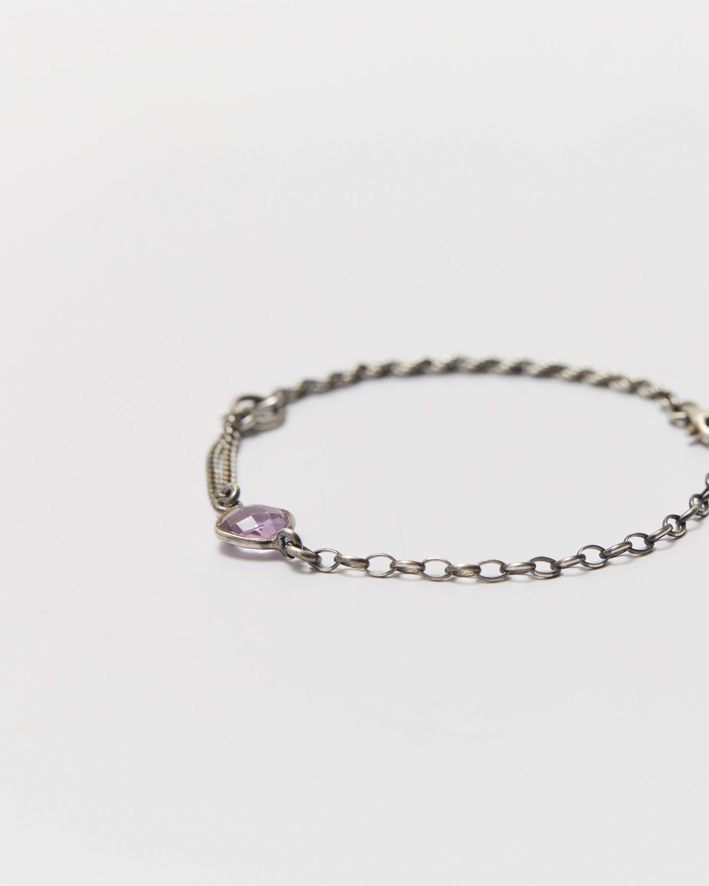 antique silver bracelet with an amethyst gemstone on a light gray background