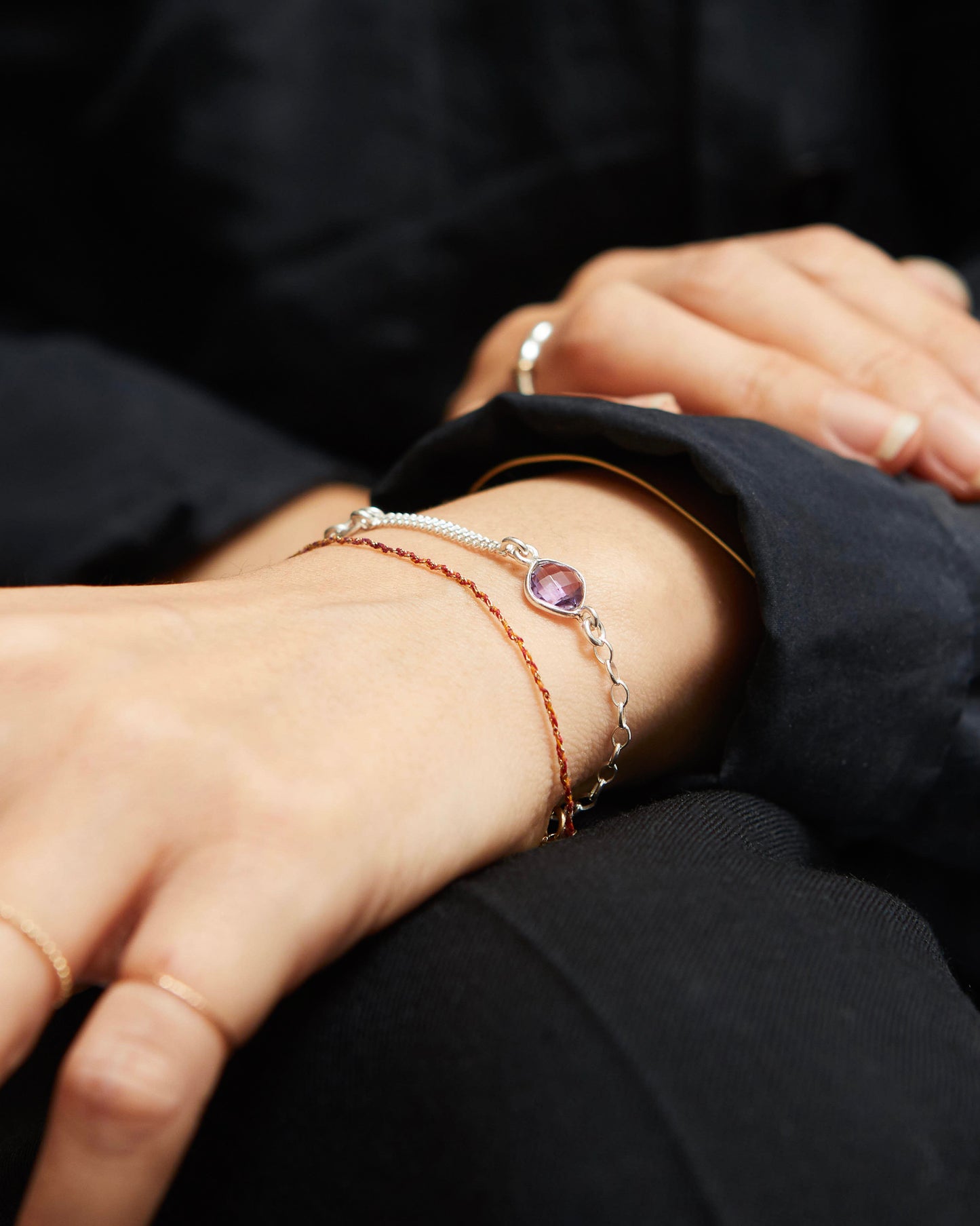 Close-up of a person's wrist wearing multiple bracelets with a dark background